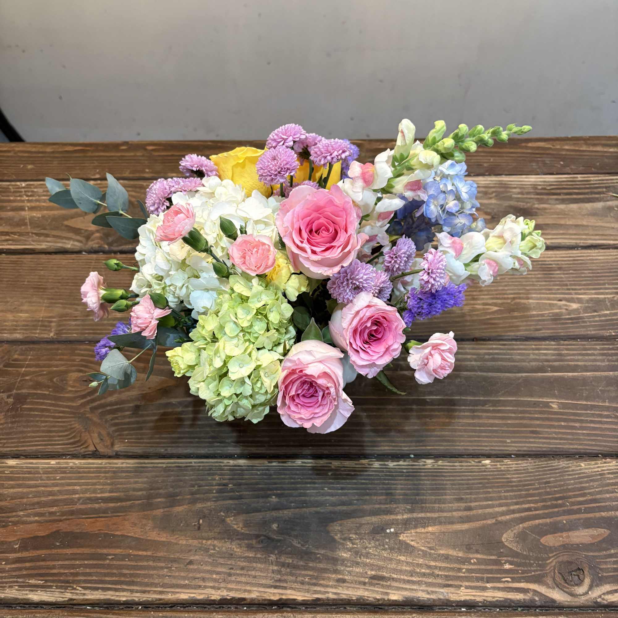 Soft blush roses and pale green hydrangea create a gentle, garden-fresh centerpiece