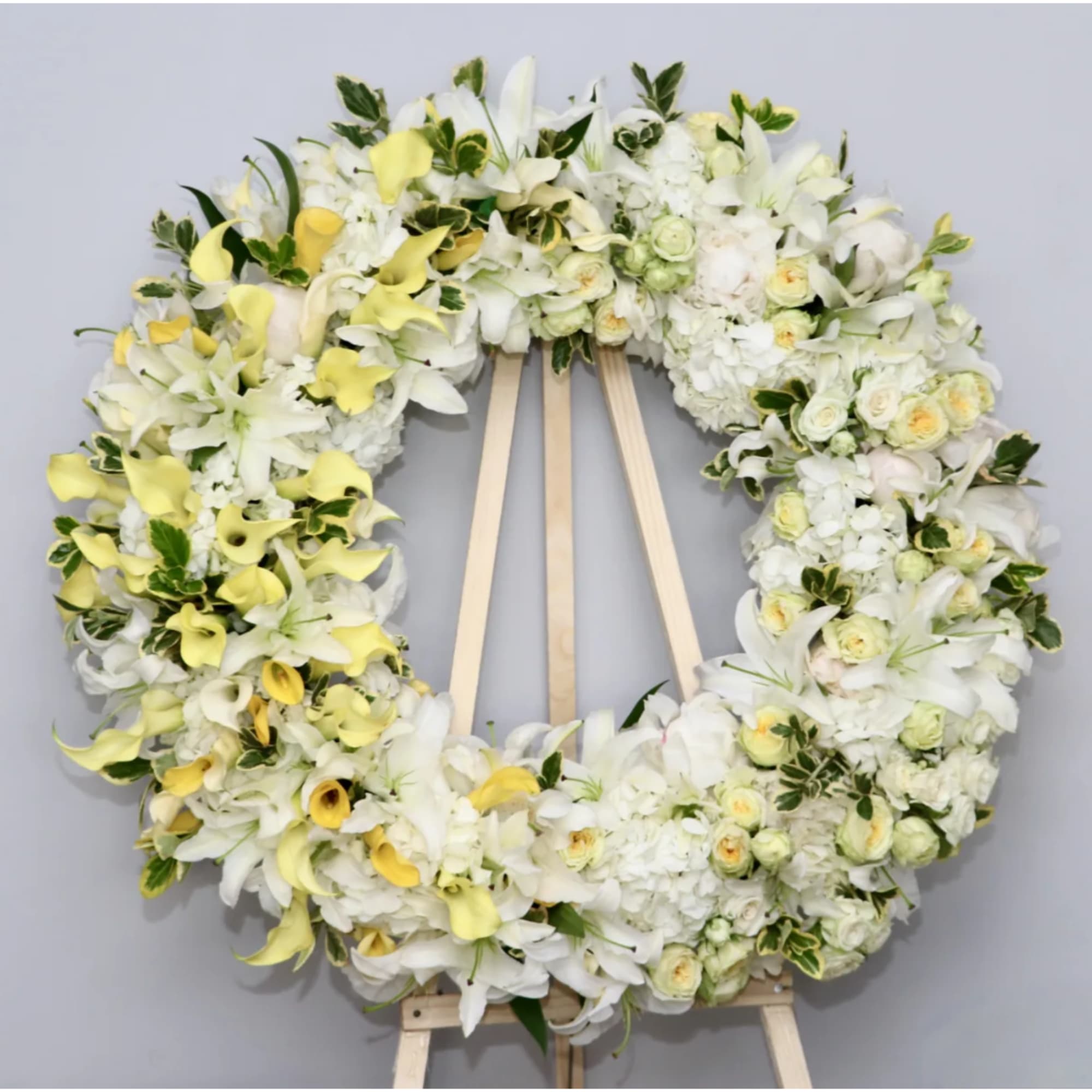 Large white and yellow floral wreath on a wooden easel