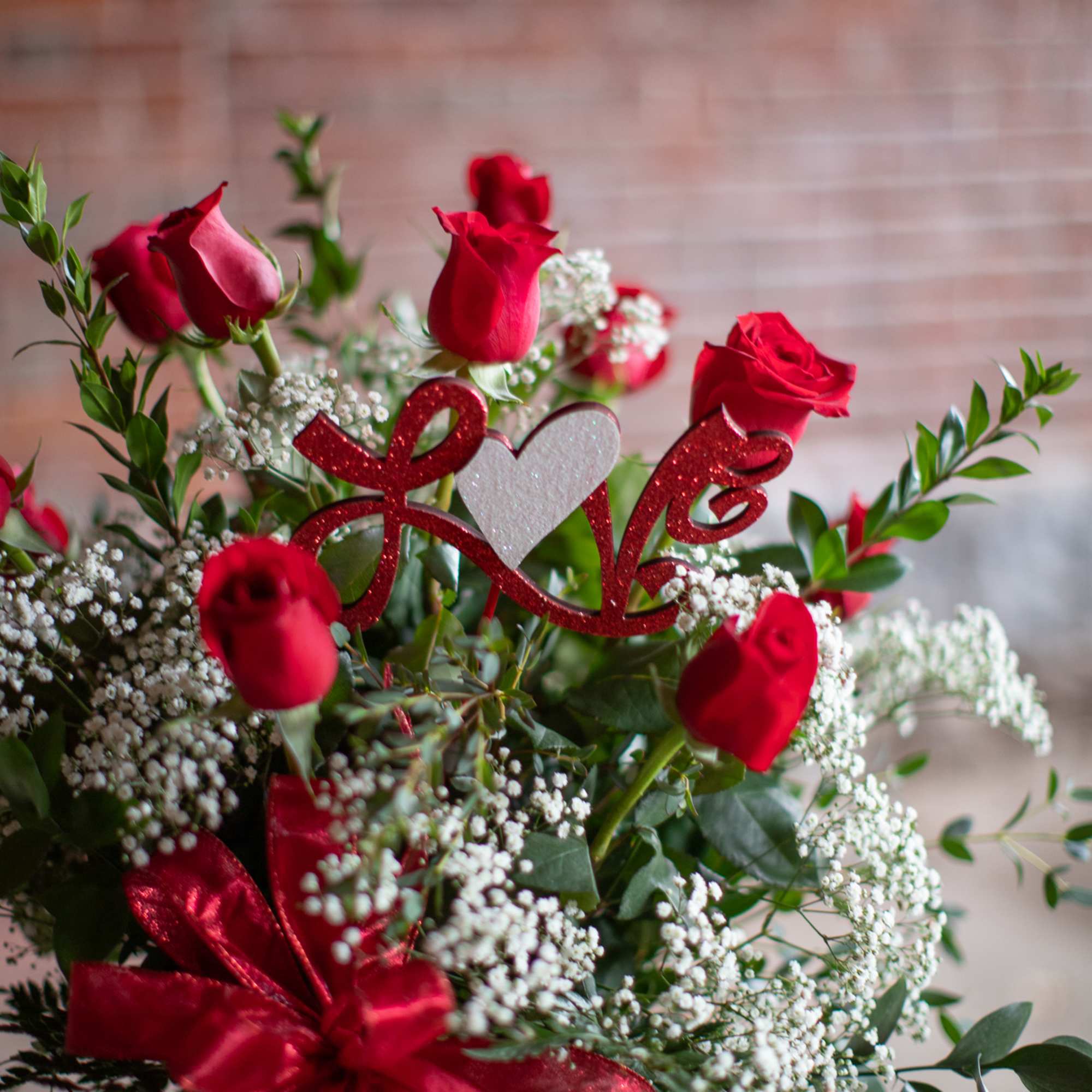 Bouquet of red roses with baby's breath and a red ribbon in a glass vase