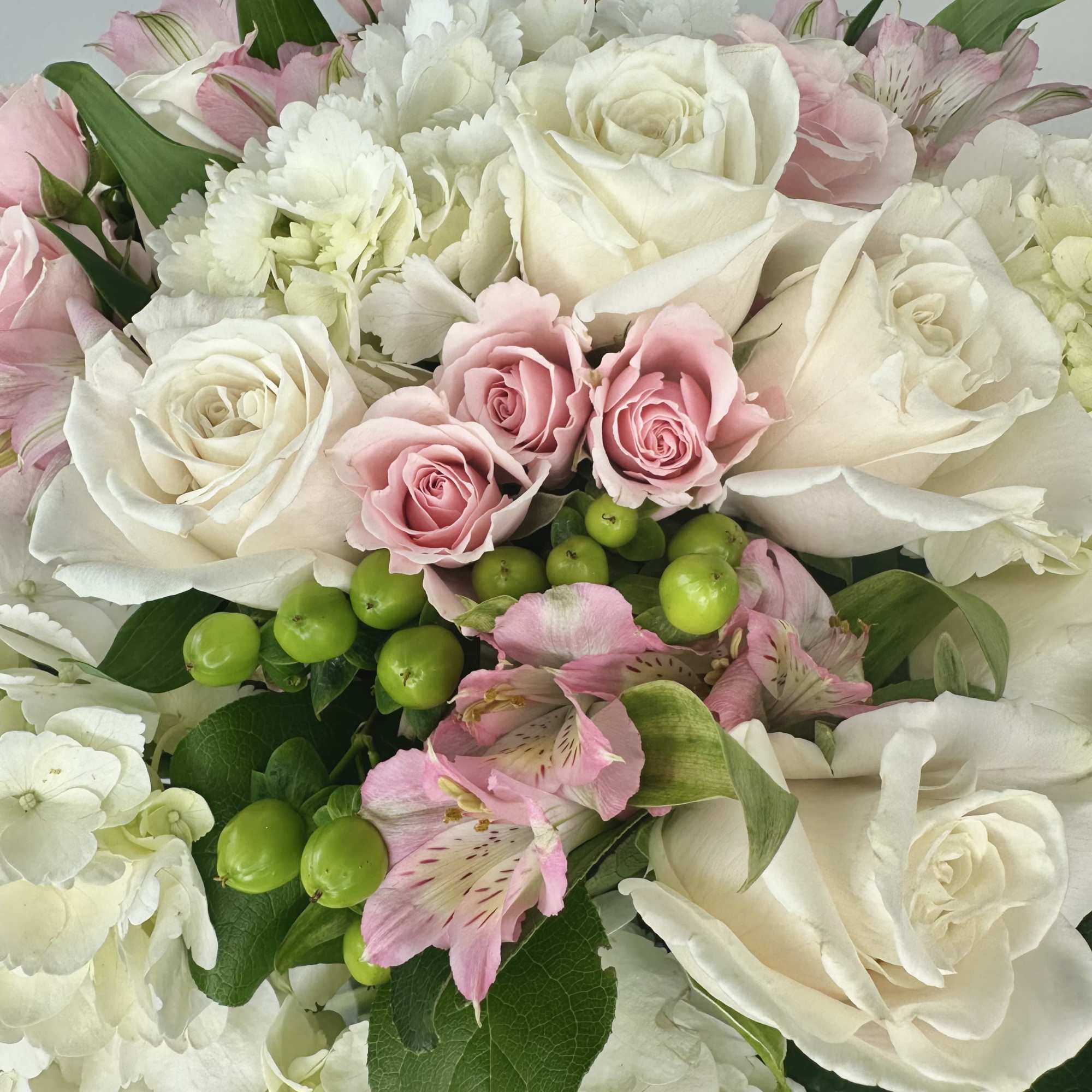 Bouquet of white and pink roses with white hydrangeas and green berries