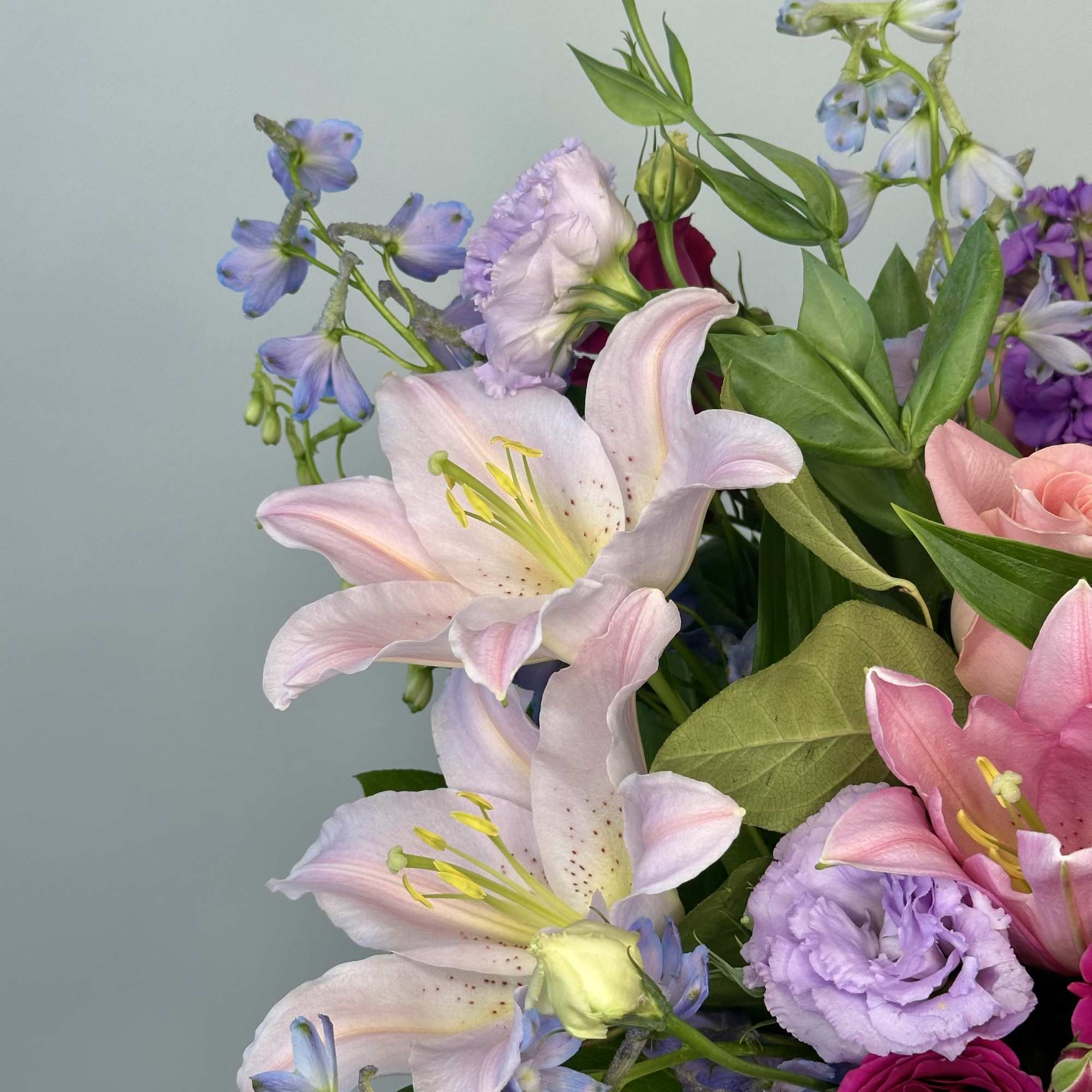 Bouquet of pink lilies, purple blooms, and blue flowers