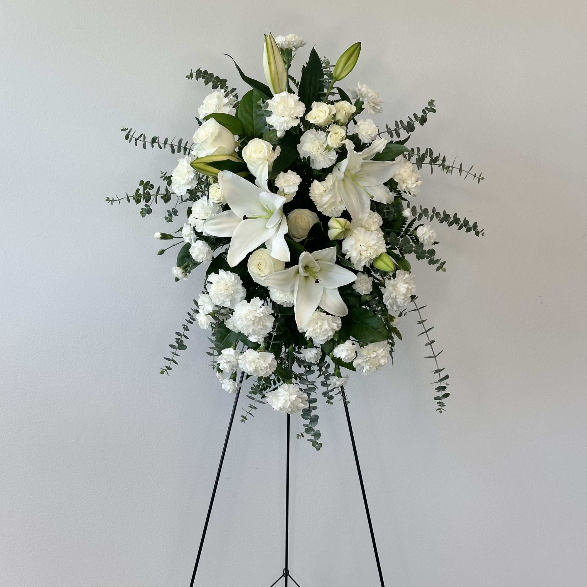 White floral standing spray on a black easel