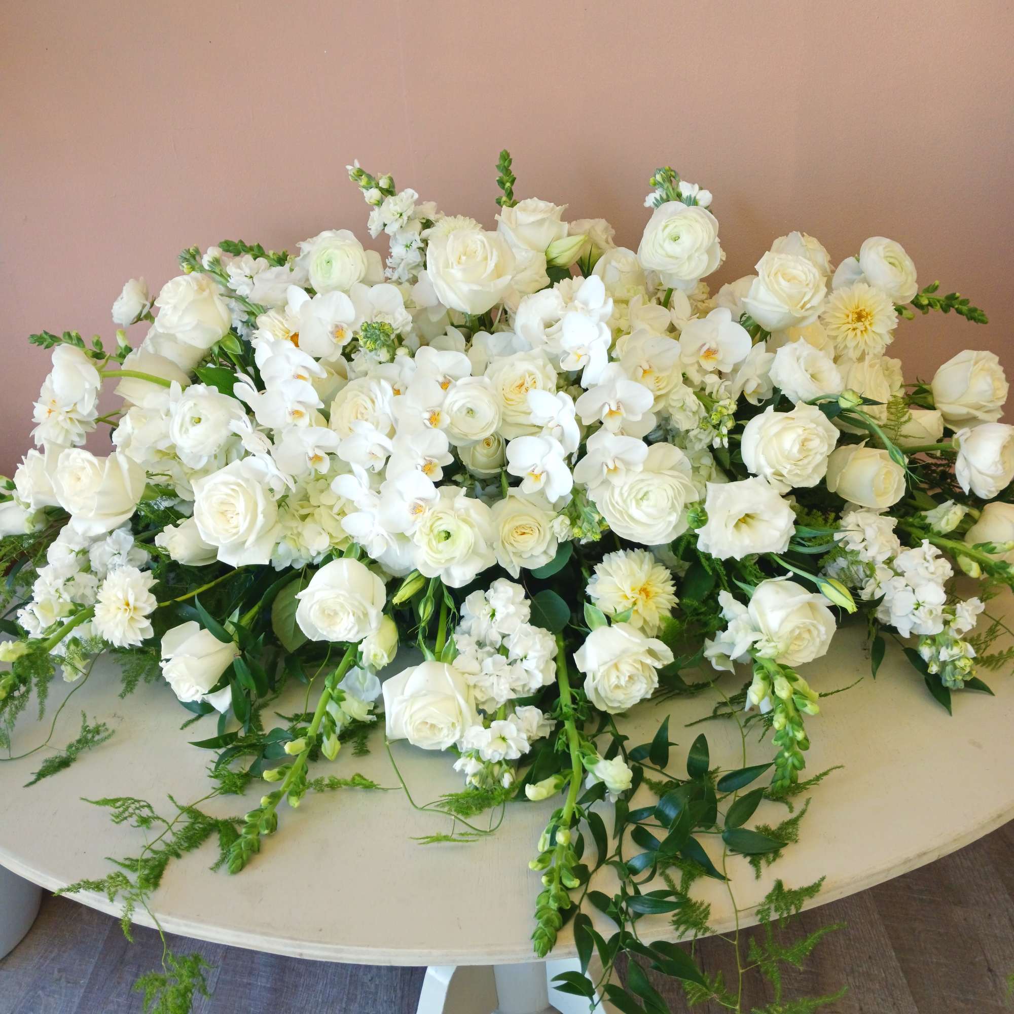 An all white casket spray with all premium flowers. This piece is
