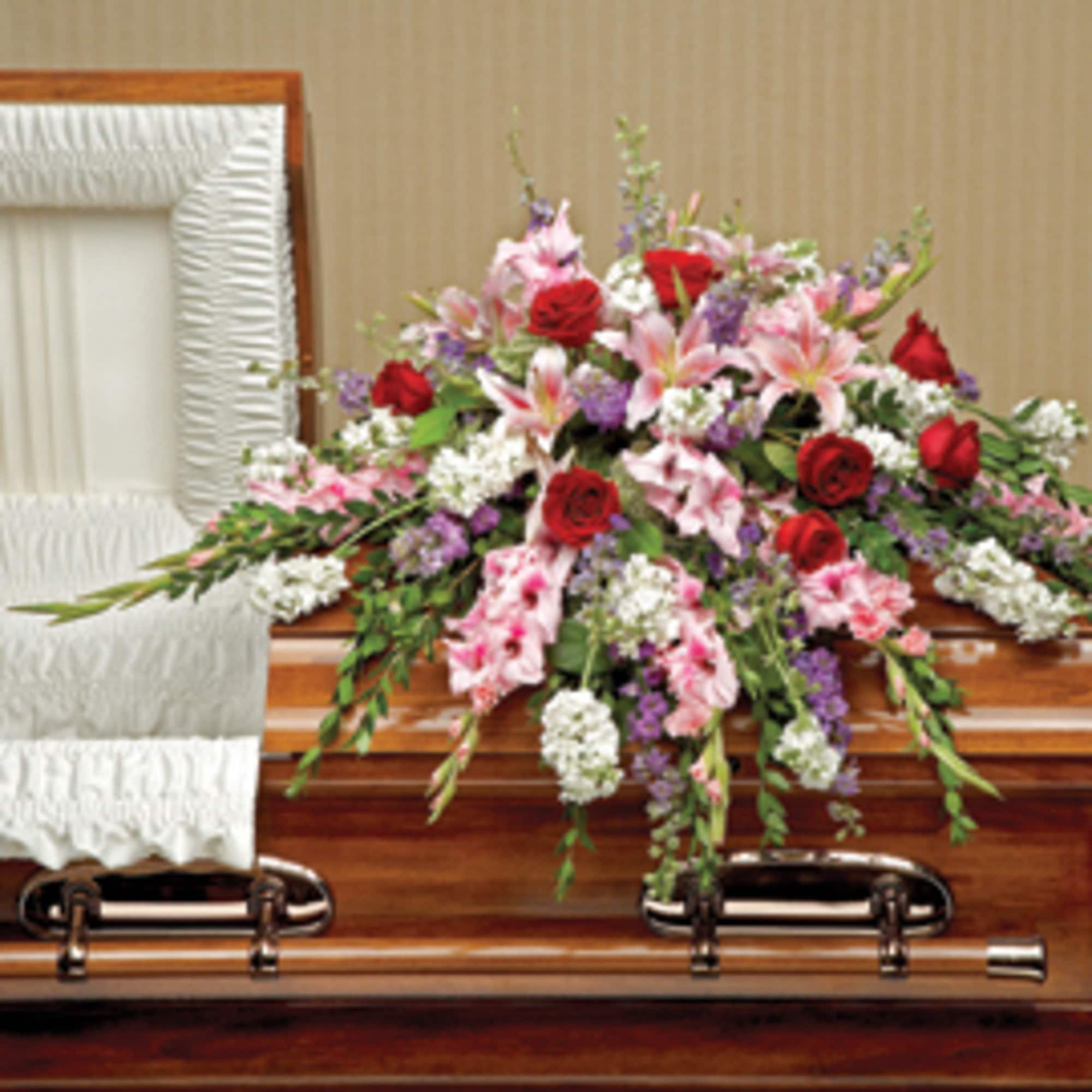 Casket spray with red roses, pink lilies, and white flowers