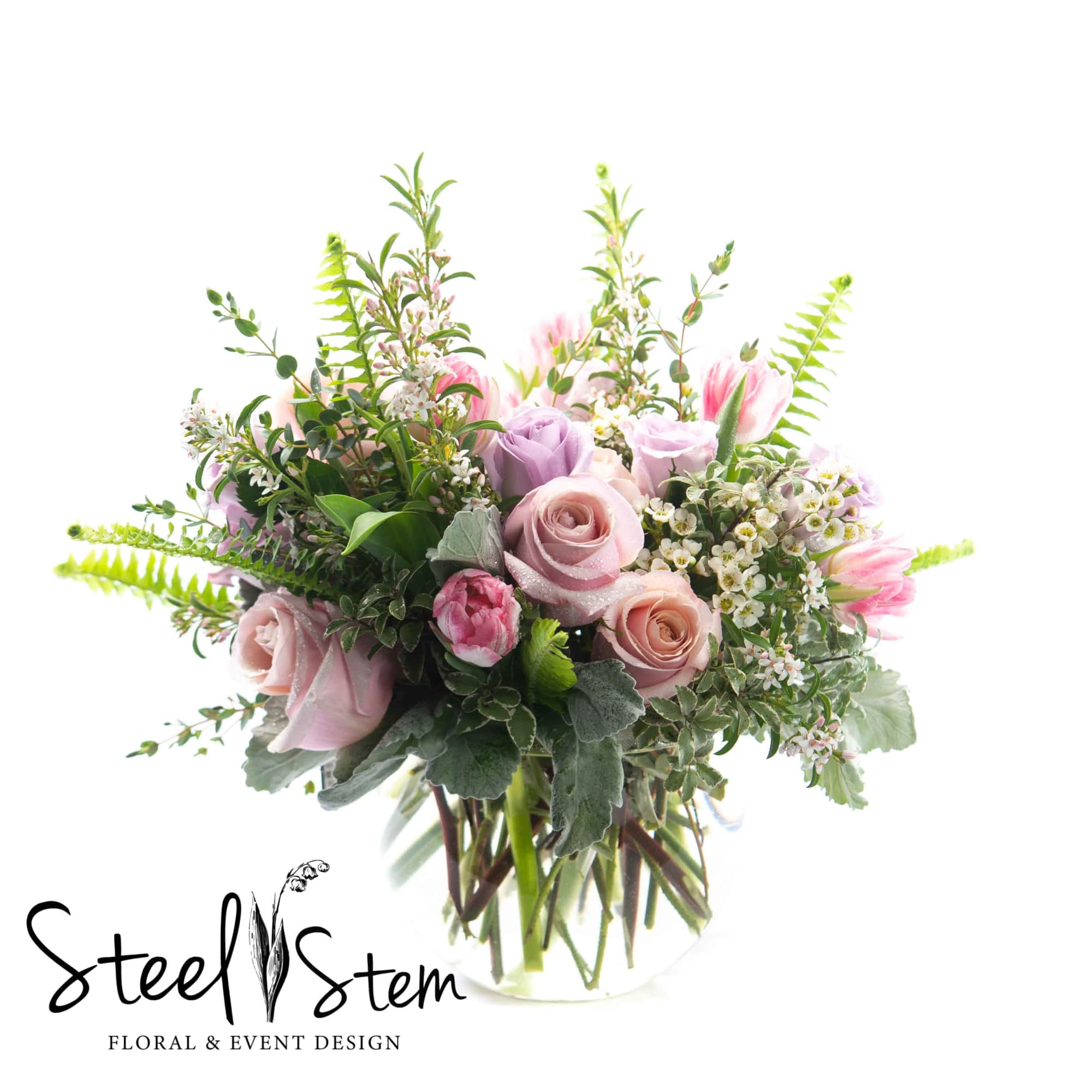 Pink and lavender rose bouquet with mixed greenery in a clear vase