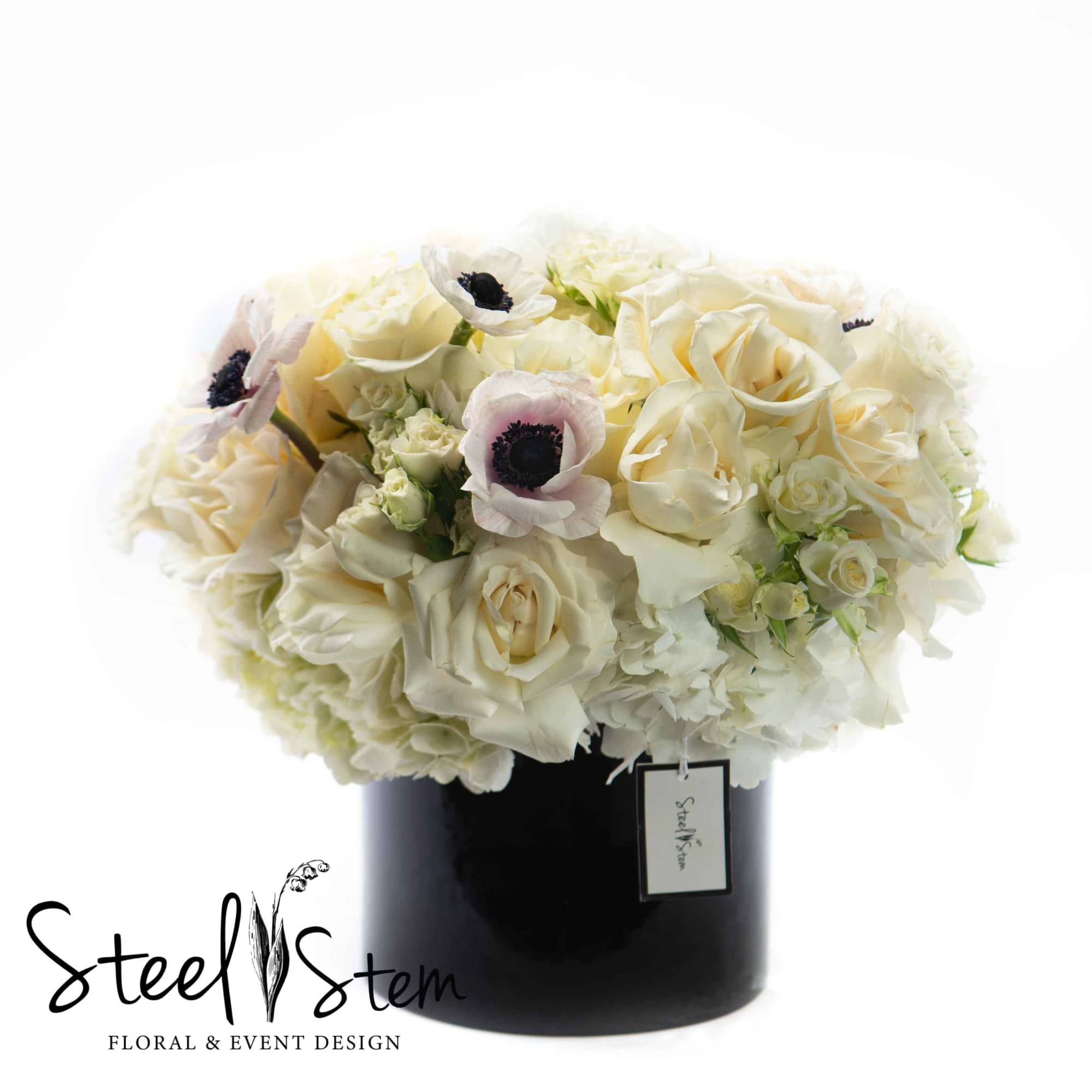 Cream roses and white anemones in a black vase