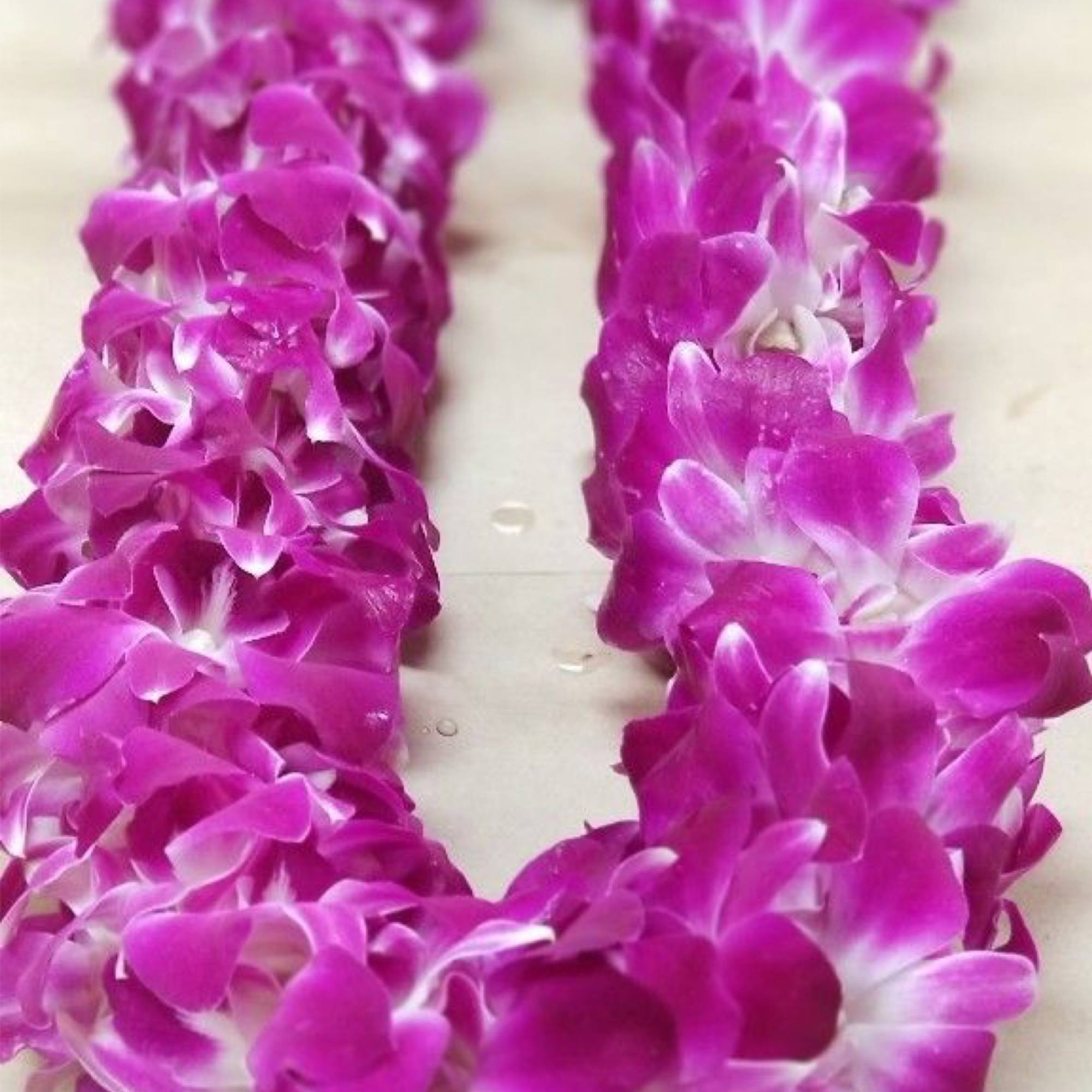 Two purple orchid leis on a light surface