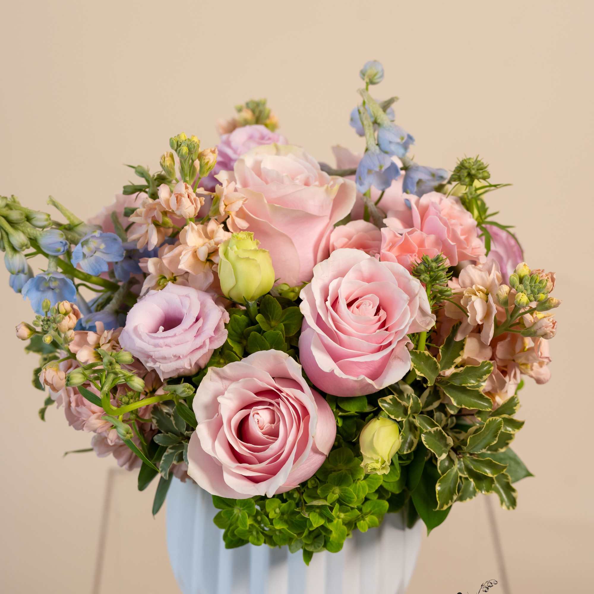 Pink roses and pastel flowers arranged in a white vase