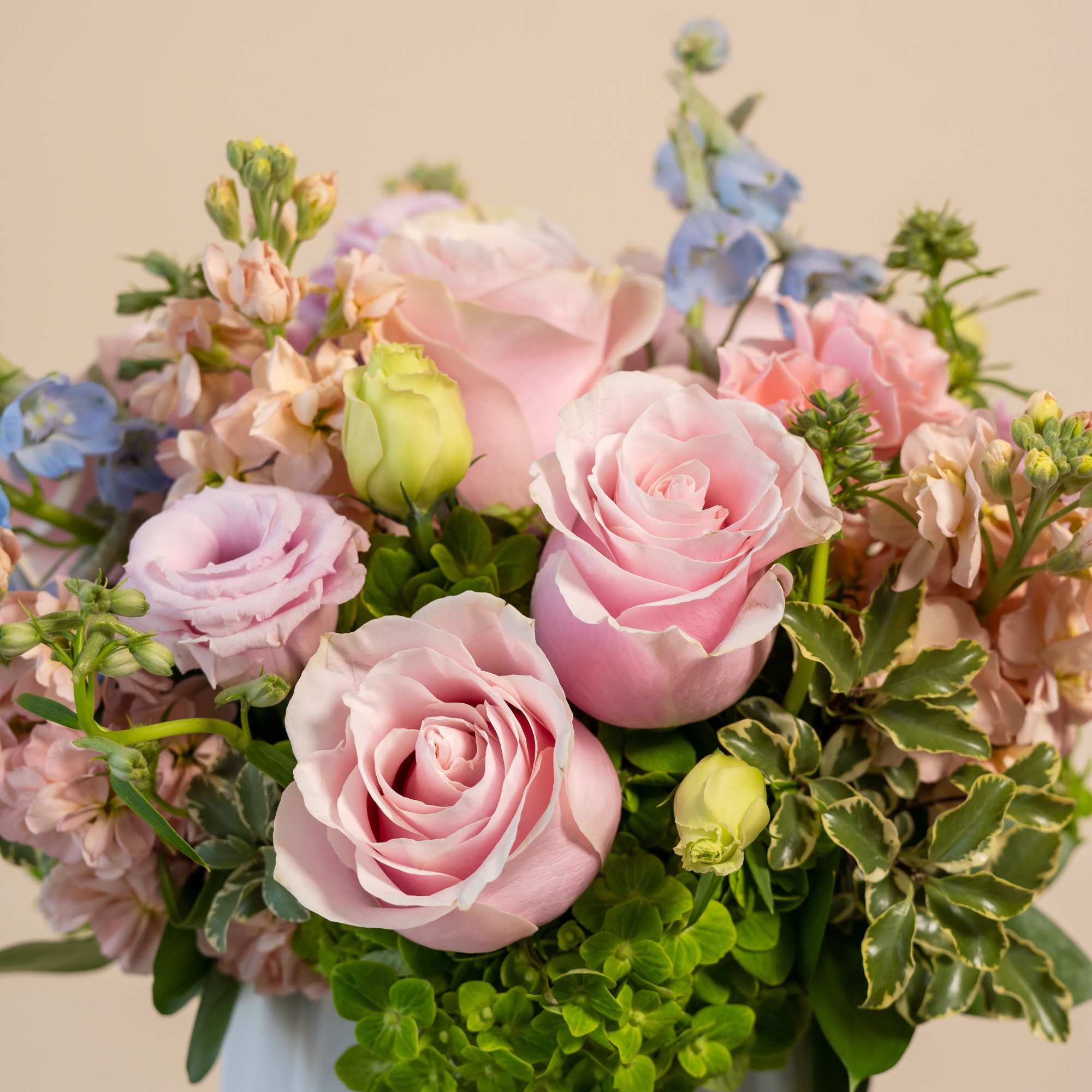 Pink roses and pastel flowers arranged in a white vase