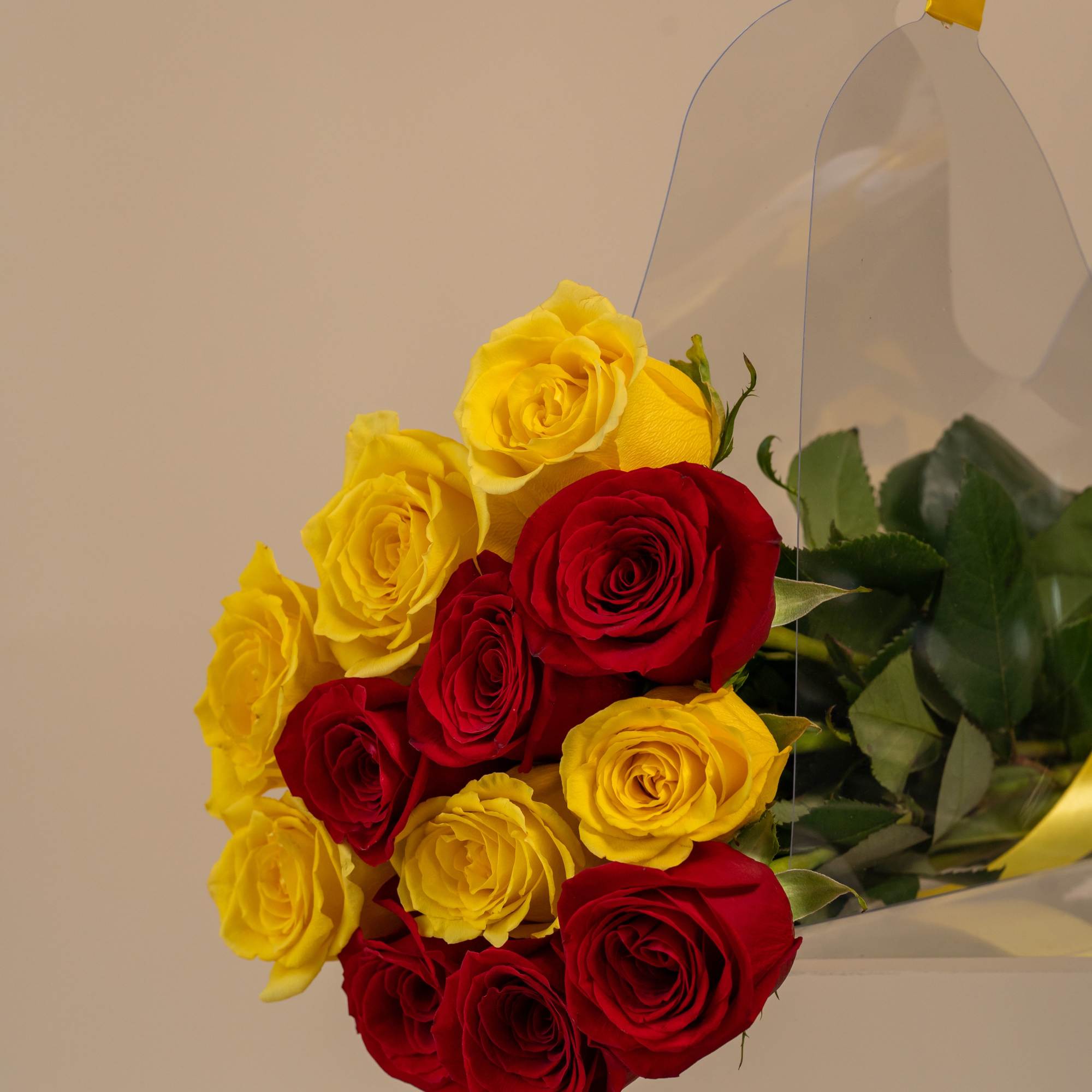 Bouquet of red and yellow roses wrapped in clear plastic