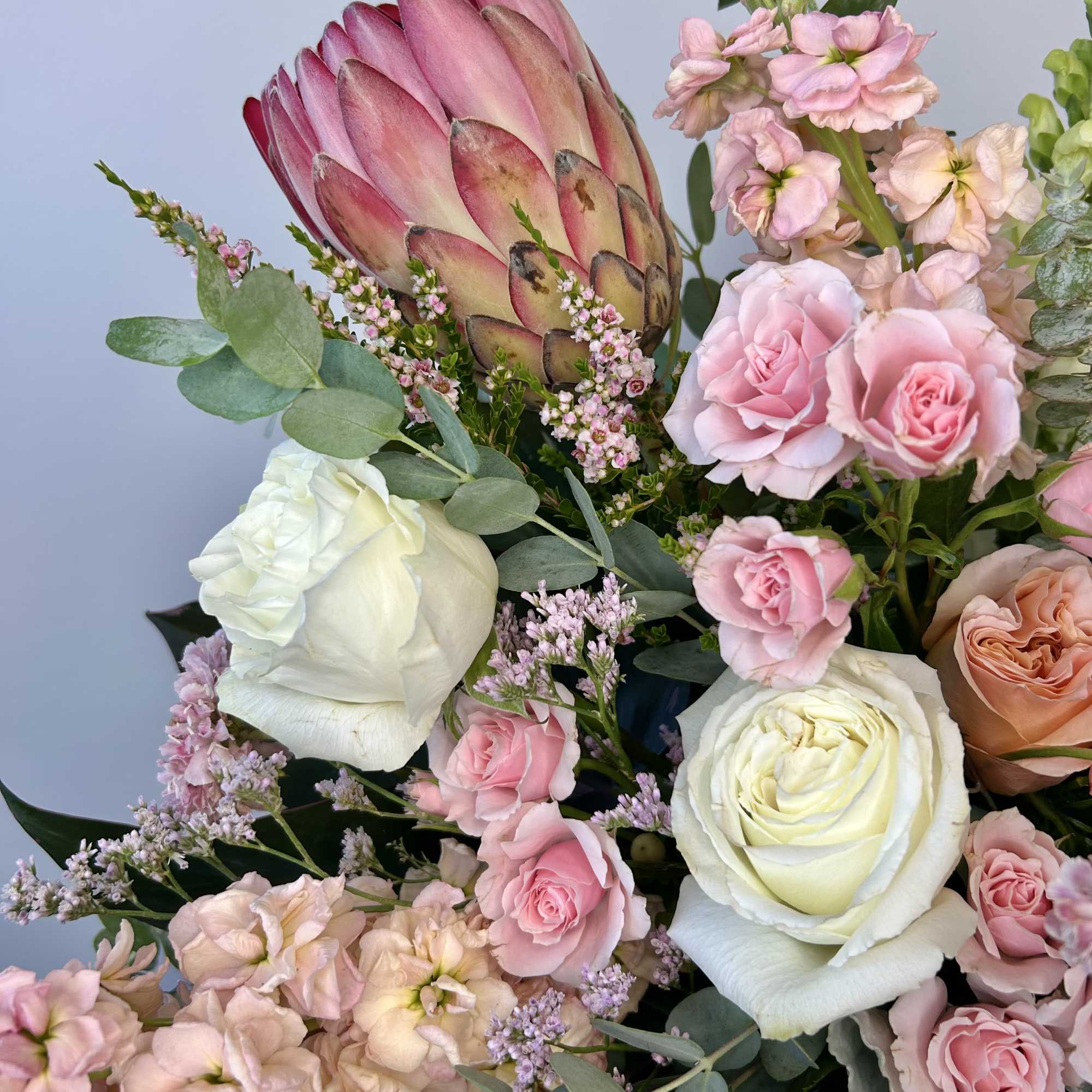 Bouquet of pink and white roses with a large protea bloom