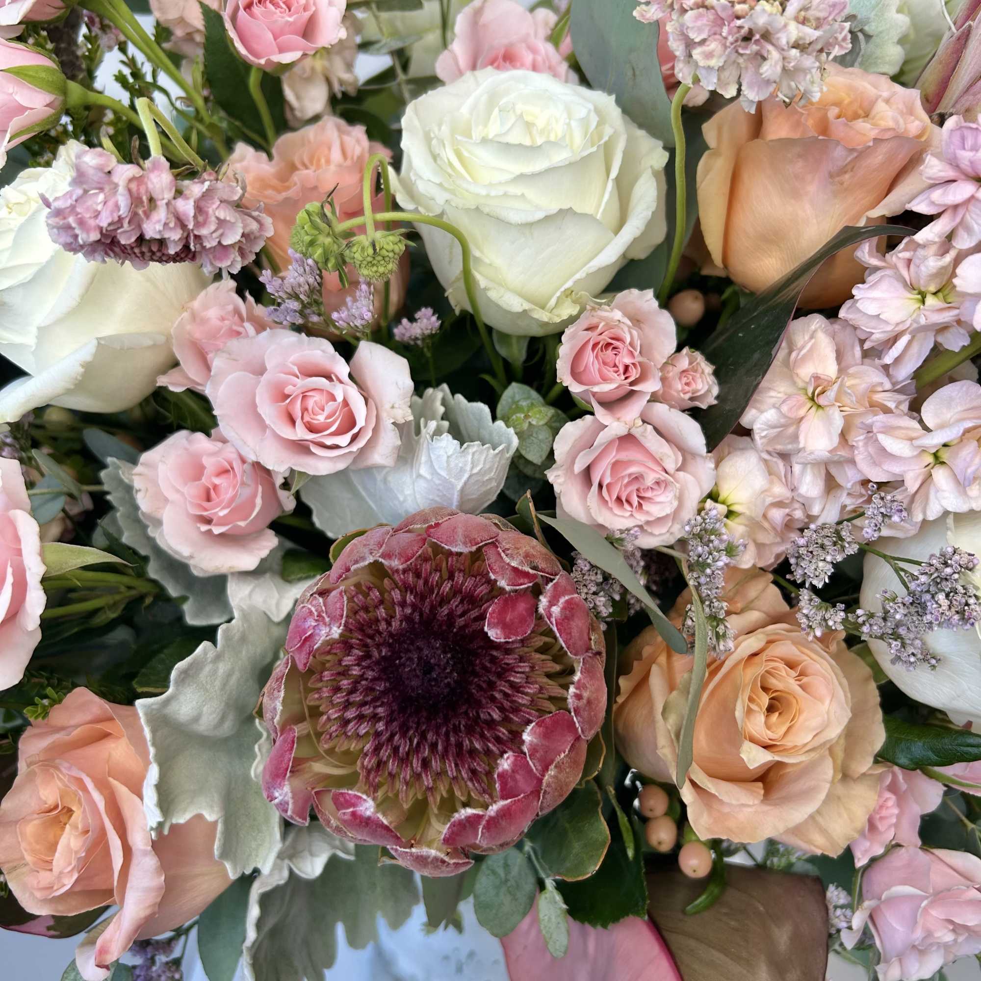 Bouquet of pink and peach roses with a white bloom and mixed flowers