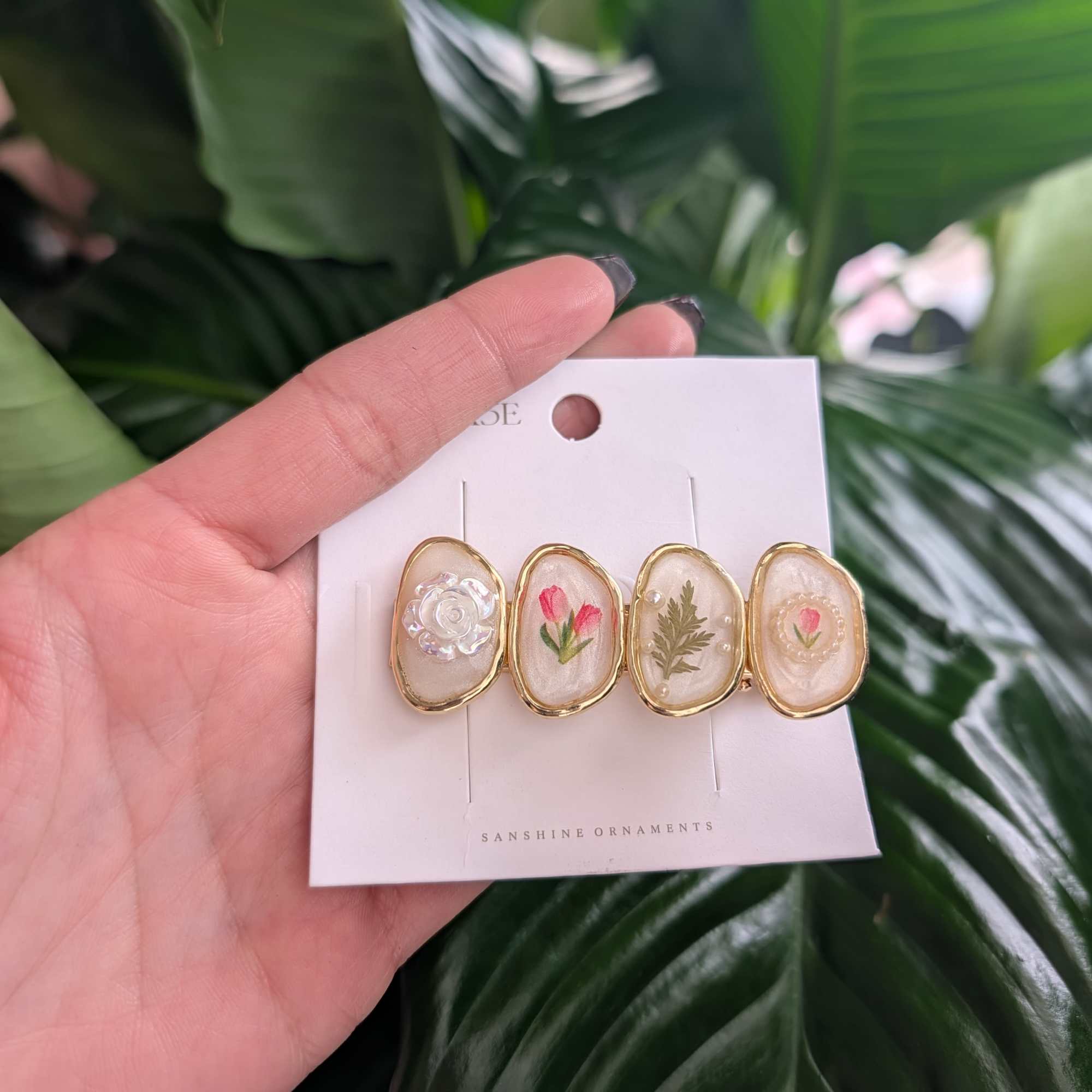 Hand holding a card with four floral resin hair clips