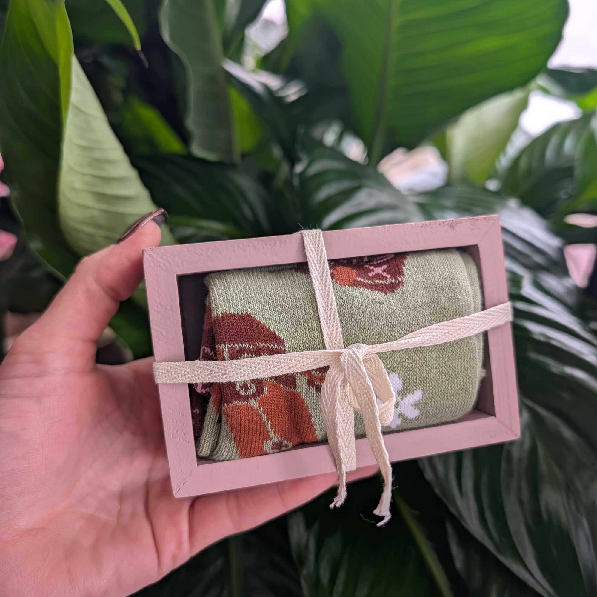 Small pink gift box tied with ribbon, held in a hand
