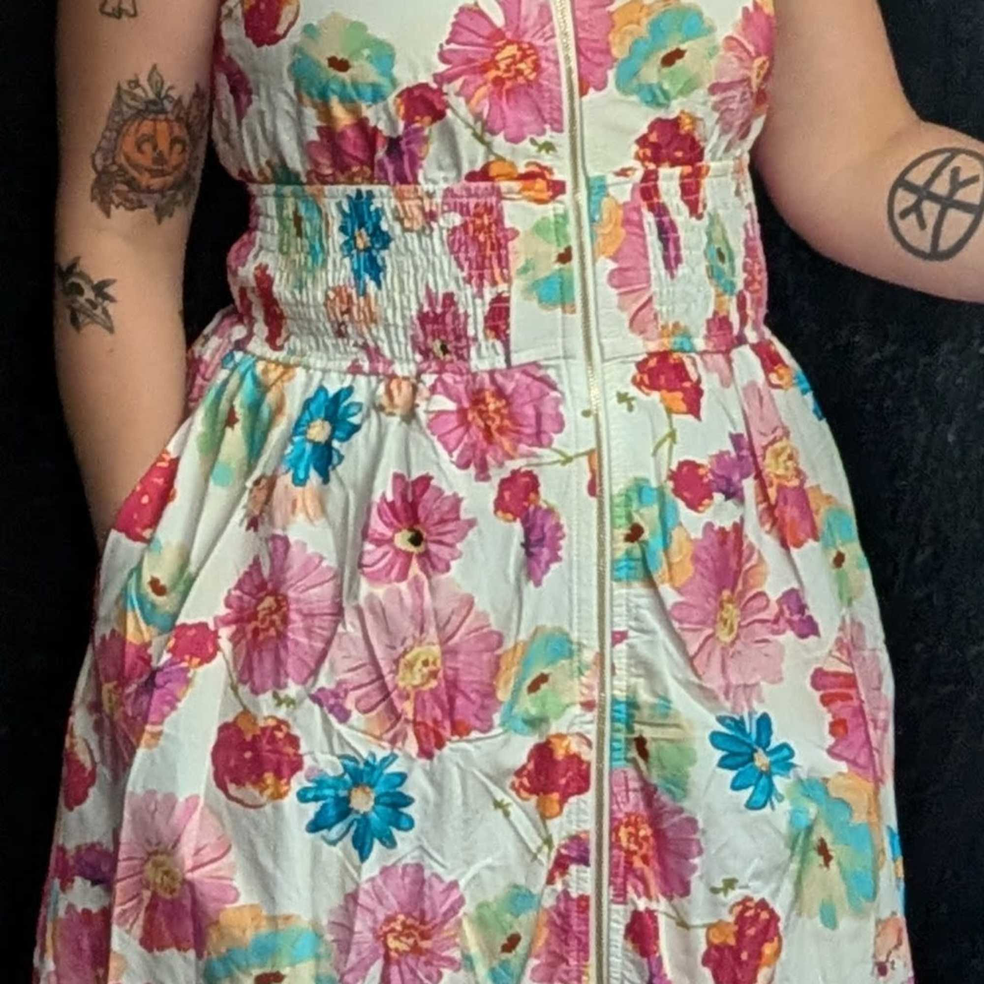 Floral sleeveless dress with a zip front and pockets. Available in sizes