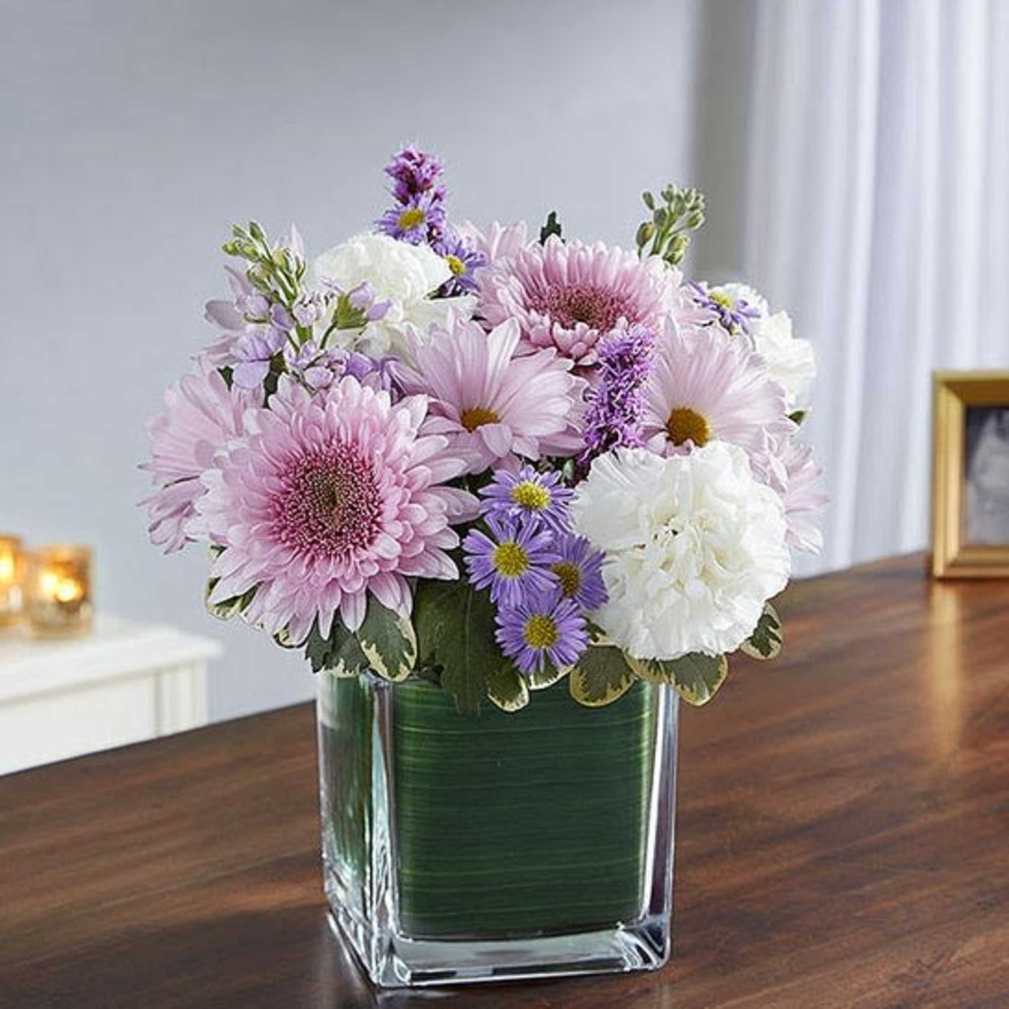 Pink and white flowers arranged in a clear square vase