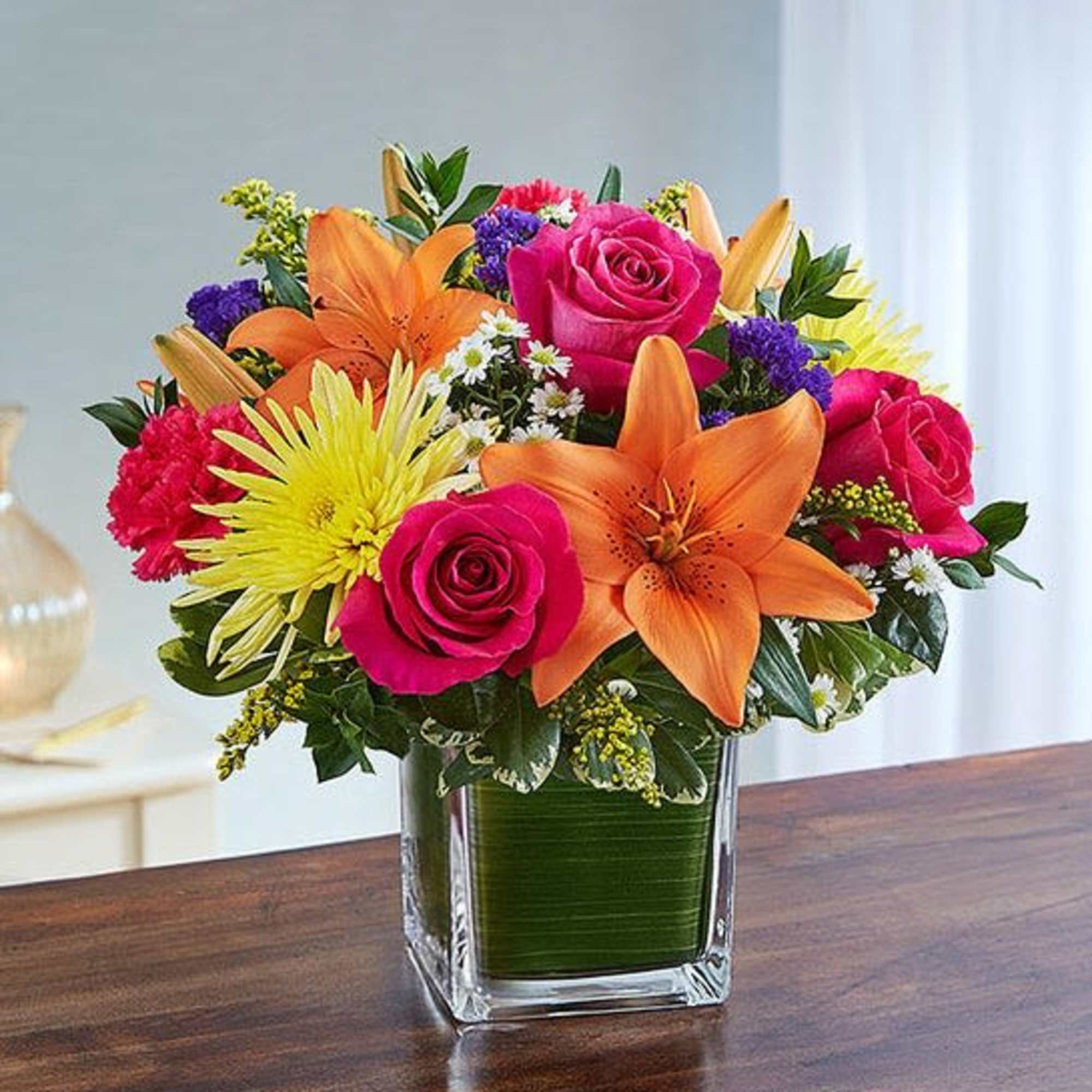 Mixed bouquet of roses, lilies, and chrysanthemums in a glass vase