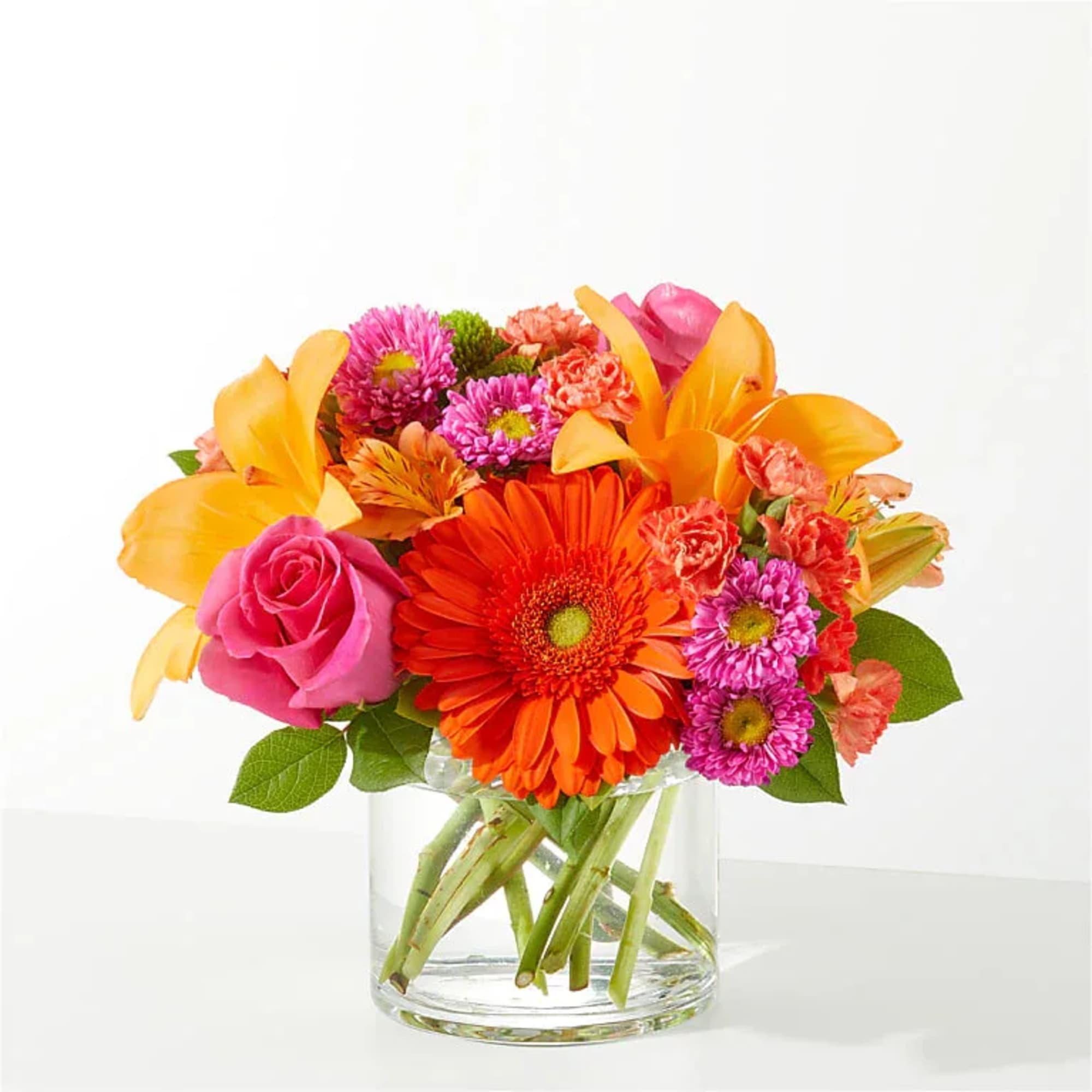 Bright mixed bouquet in a clear glass vase with orange, pink, and purple flowers.