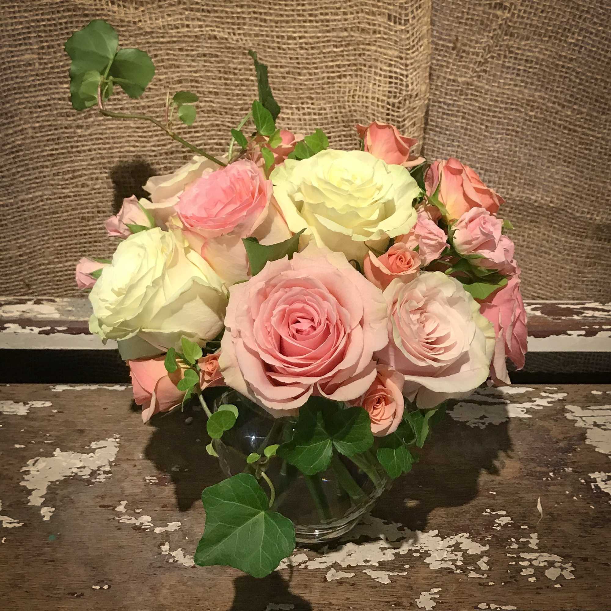 Pink and cream roses arranged in a clear glass vase