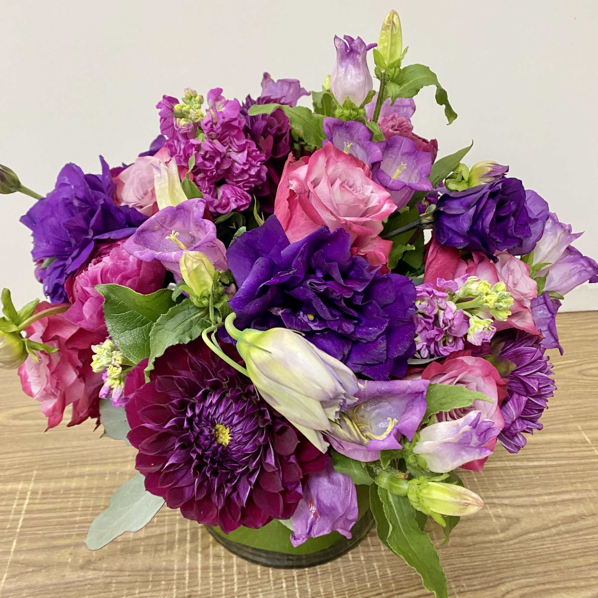 Clear glass vase with a purple lisianthus, purple roses ,lavender stock 