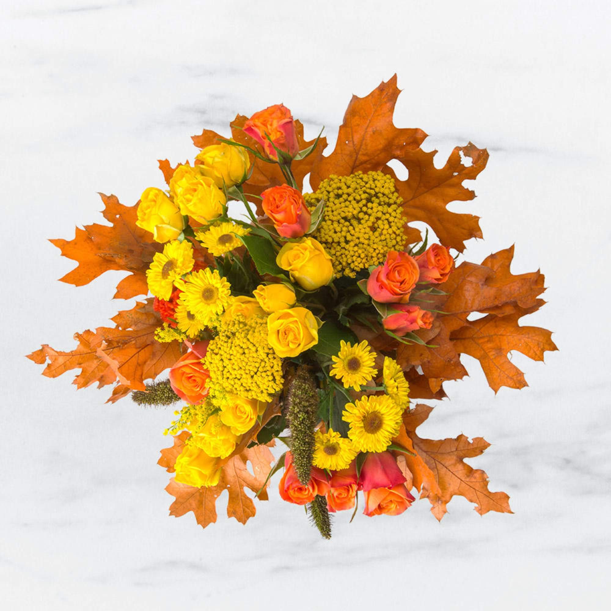 Autumn bouquet of yellow and orange roses and daisies with orange maple leaves