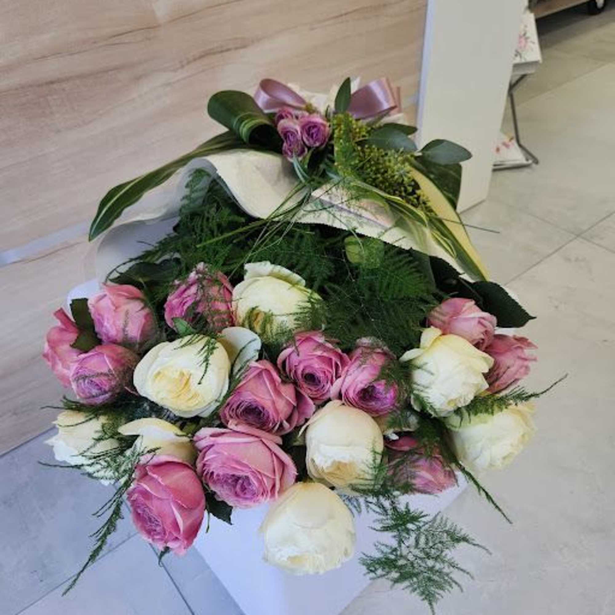 Low arrangement of pink and cream roses in a white square container with a decorative bow.