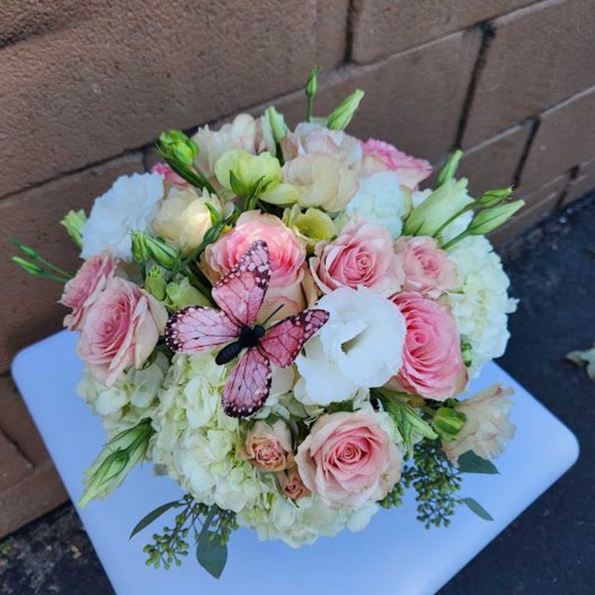 Round bouquet of pink roses and white hydrangeas with a decorative pink butterfly accent