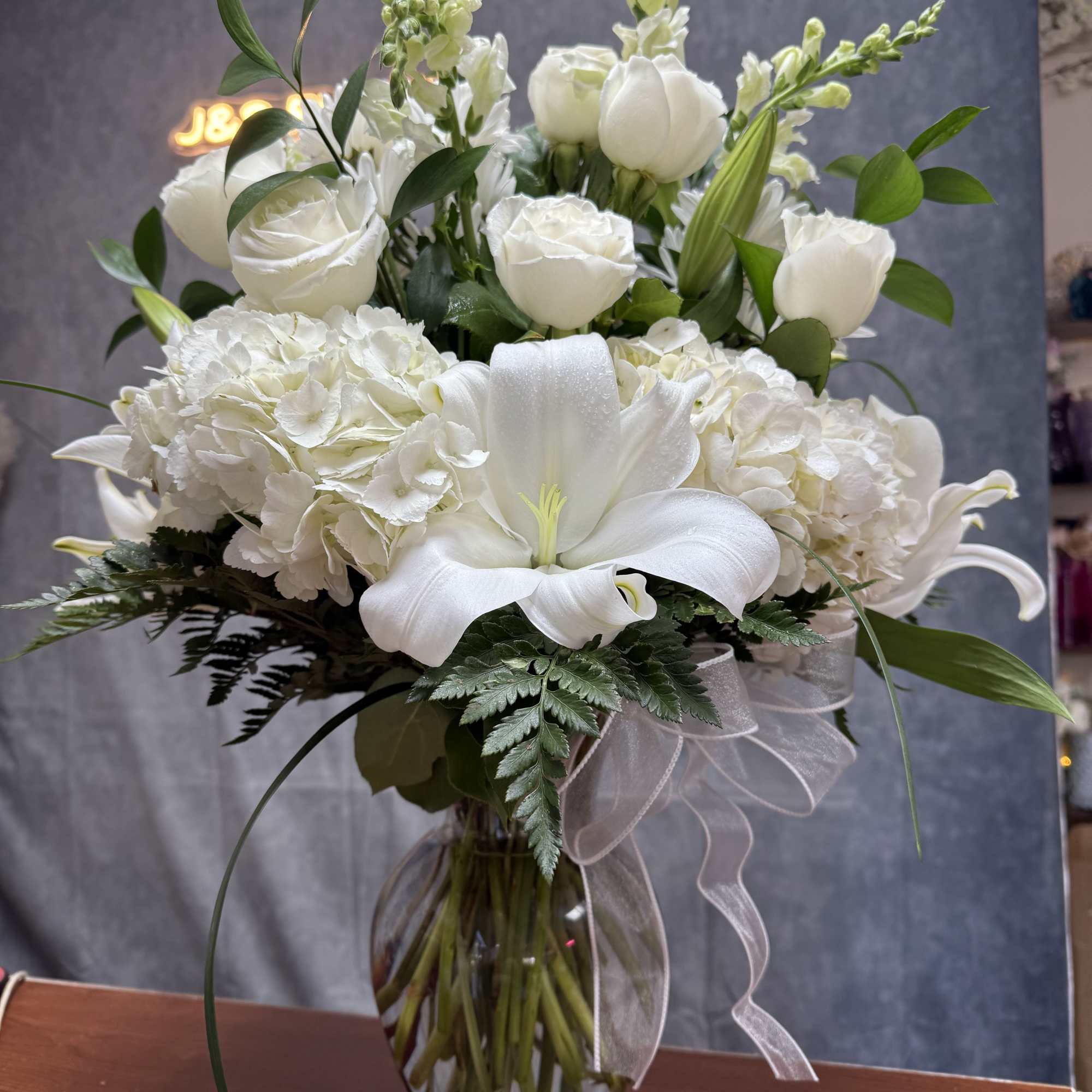 White floral arrangement in a glass vase with a sheer ribbon