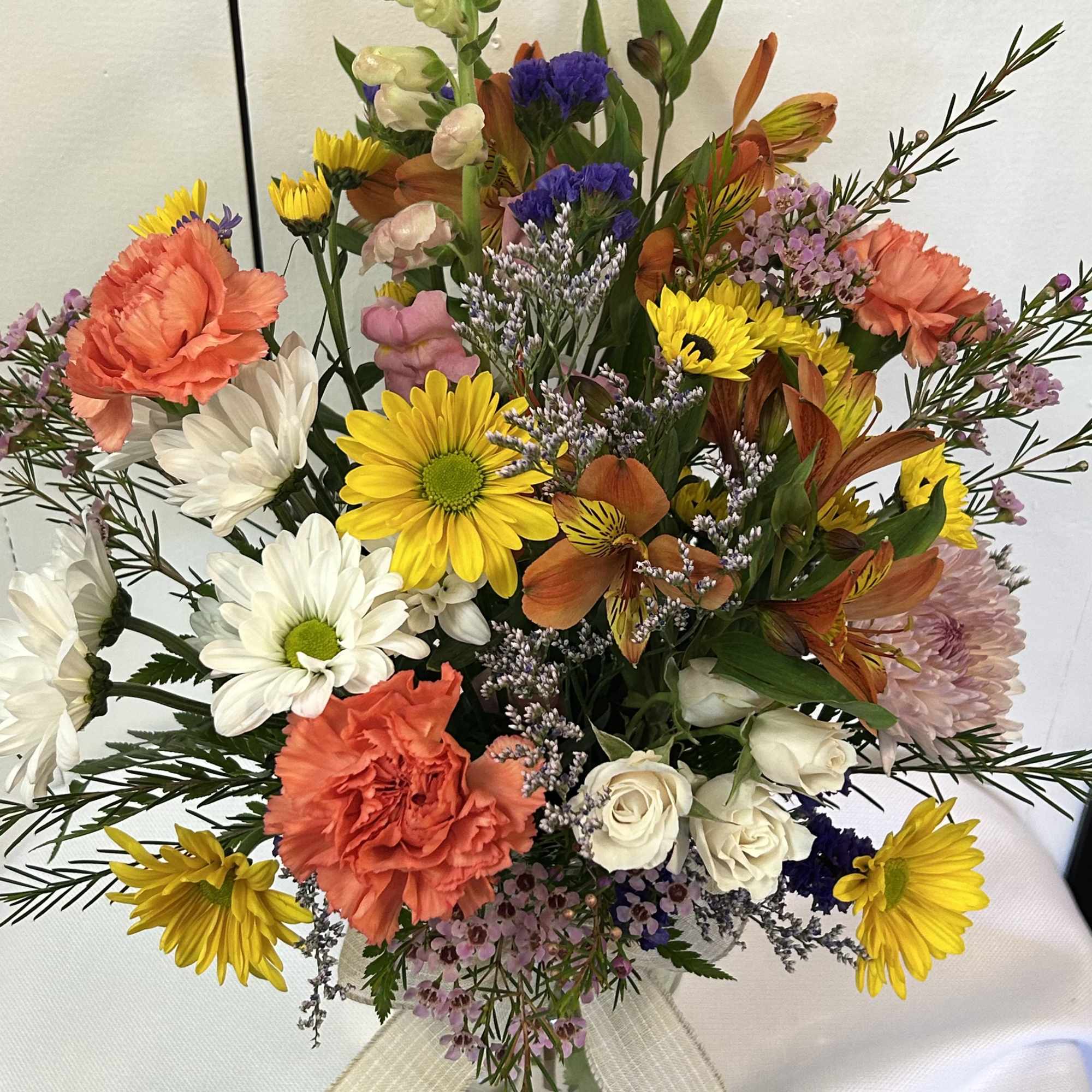 Mixed bouquet in a glass vase with yellow, white, coral, and purple flowers