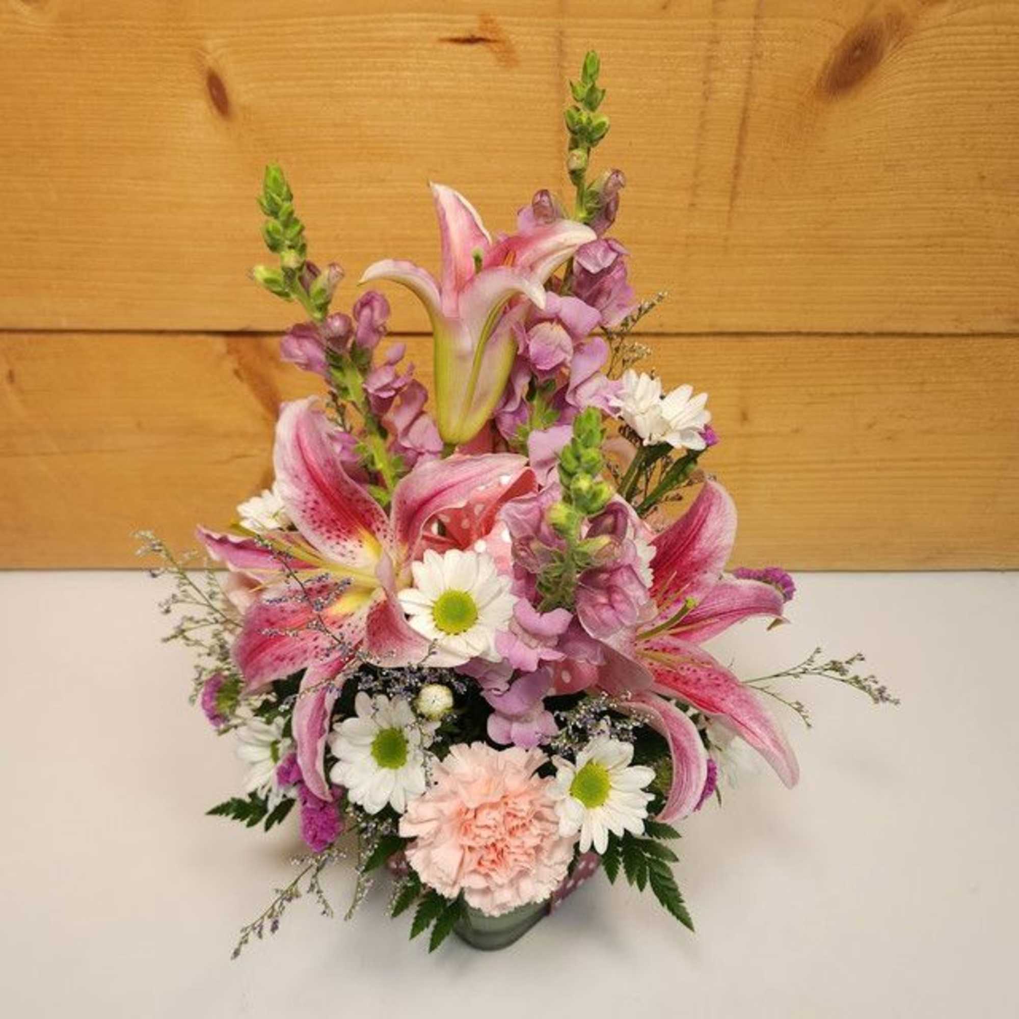 Pink lilies and purple flowers in a vase with white daisies