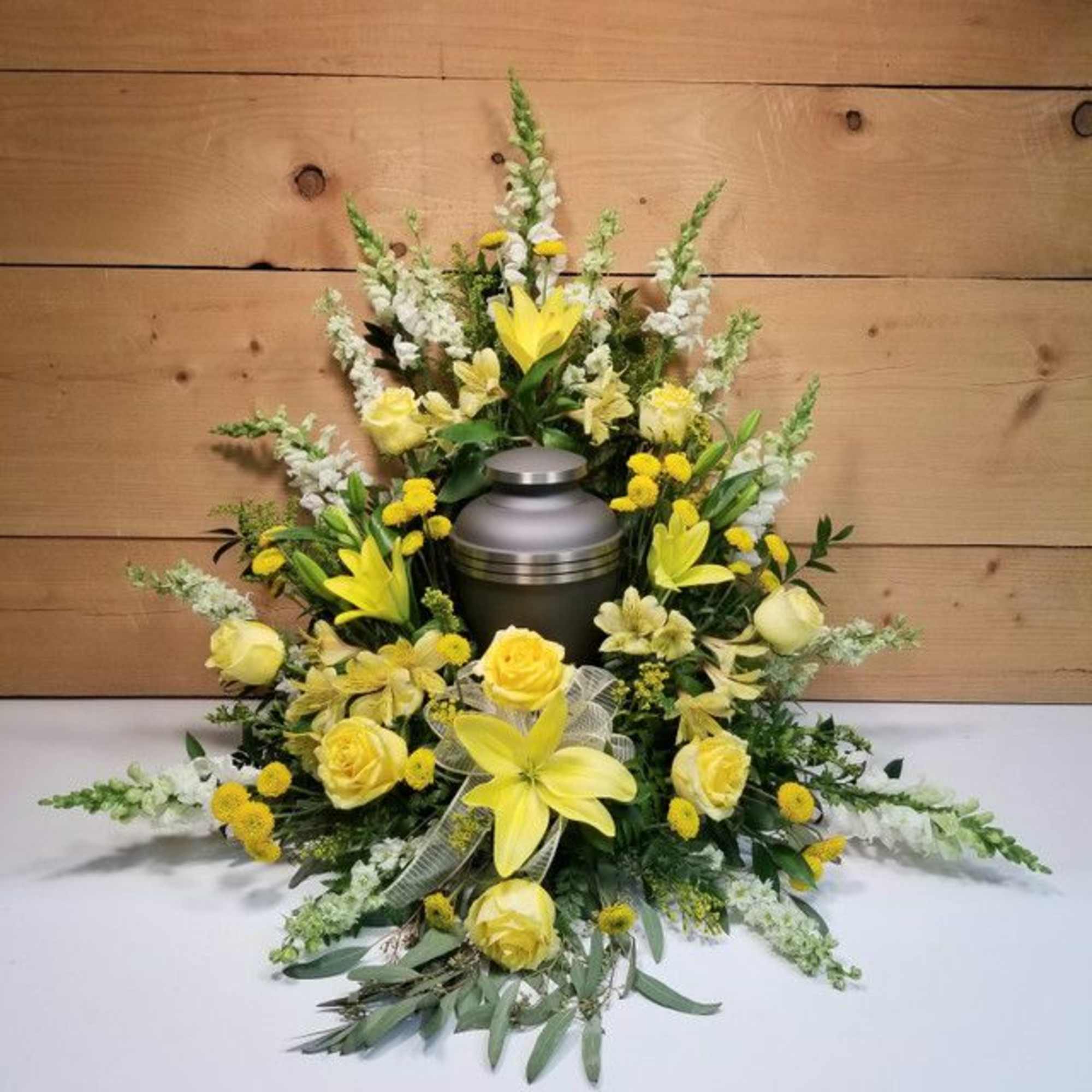 Yellow floral funeral arrangement around a silver urn
