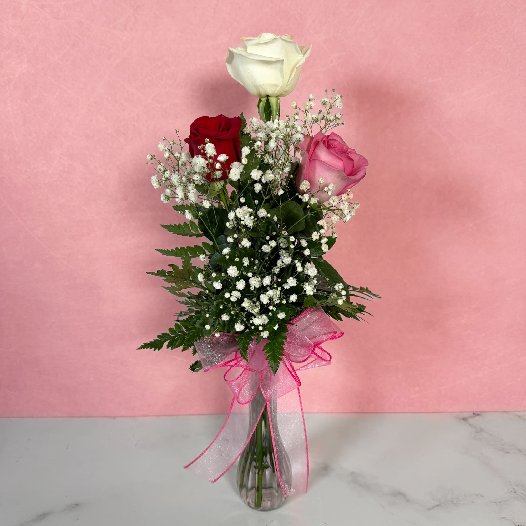 Three roses with baby's breath in a clear glass vase