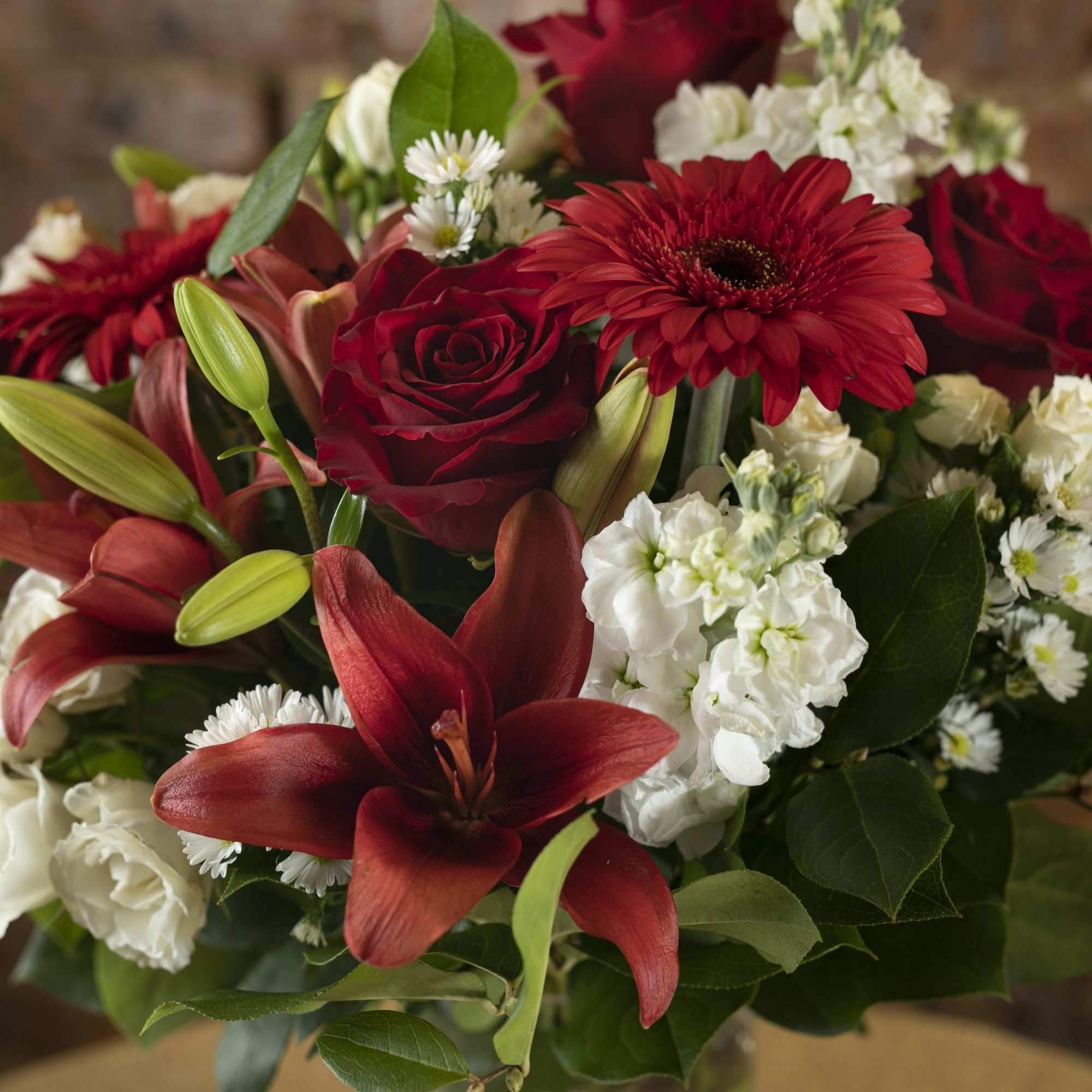 Bouquet of red roses, lilies, and white filler flowers
