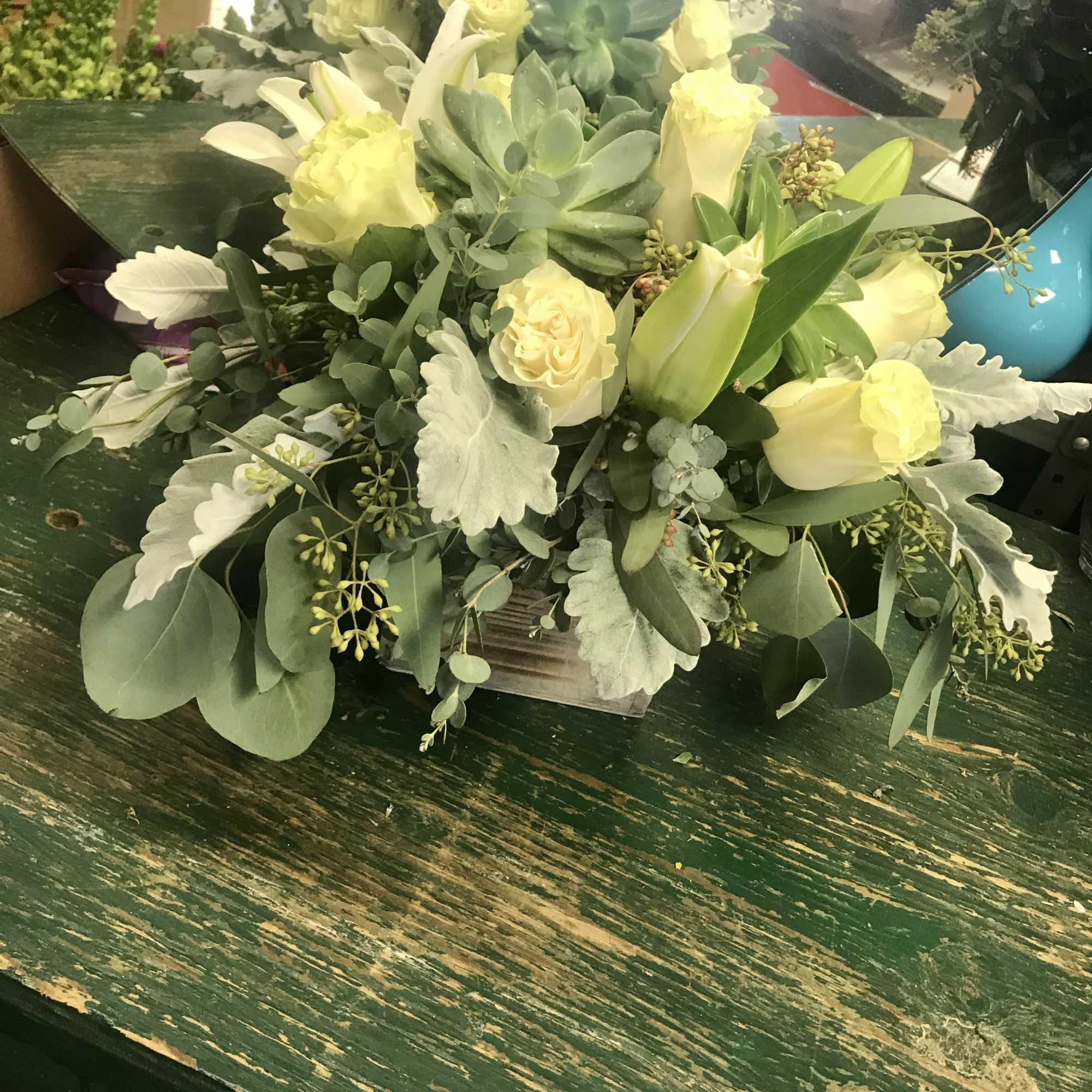 Cream roses and lilies arranged in a low wooden container