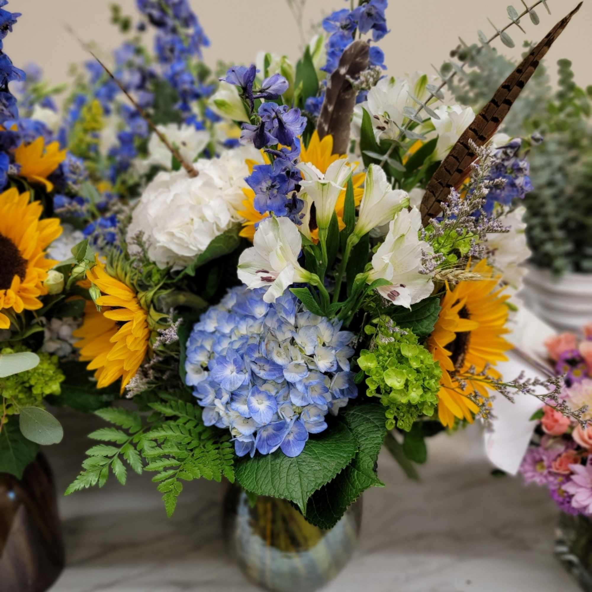 Mixed bouquet with blue hydrangea, white lilies, and yellow sunflowers in a vase