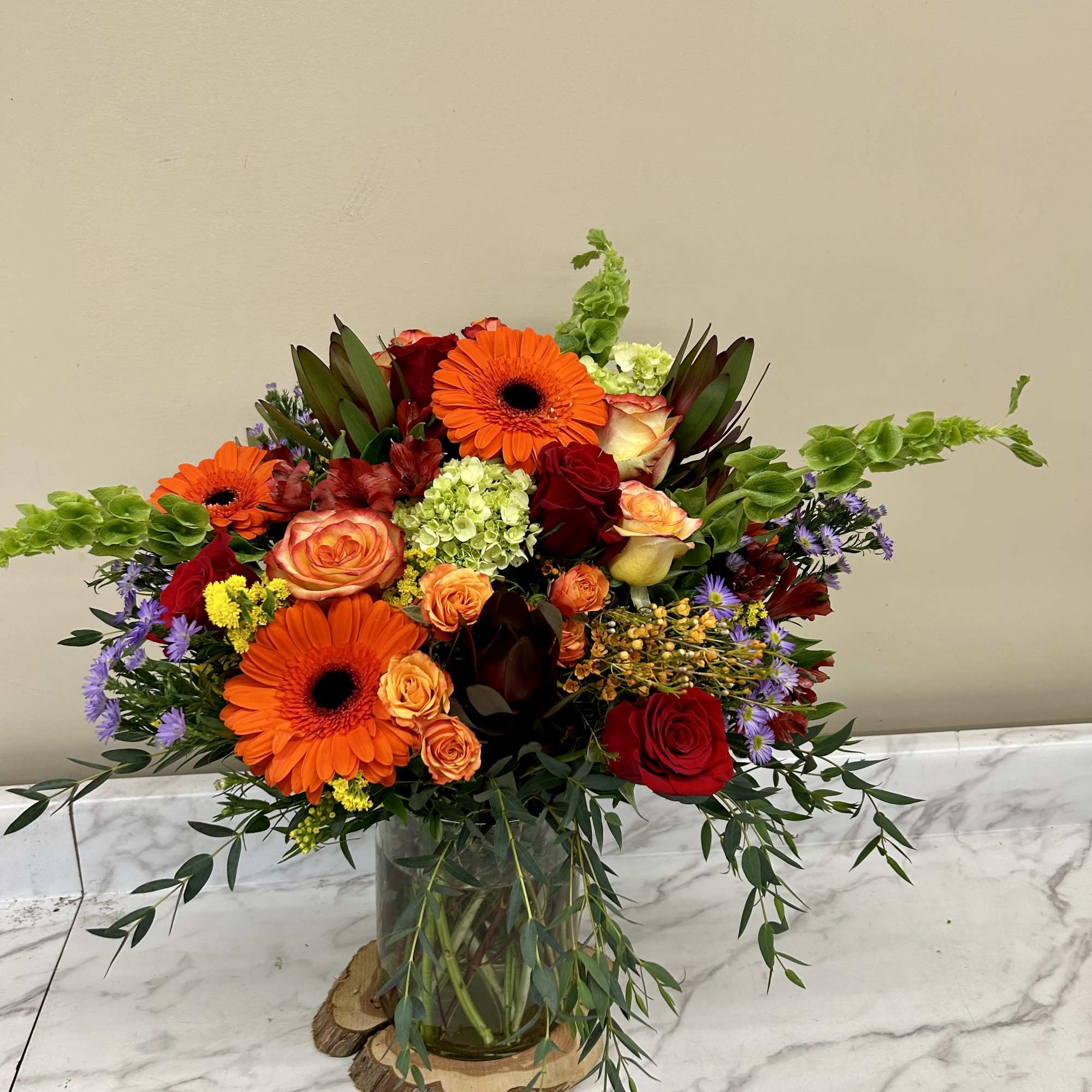 Mixed bouquet in a clear glass vase with orange gerberas and red roses