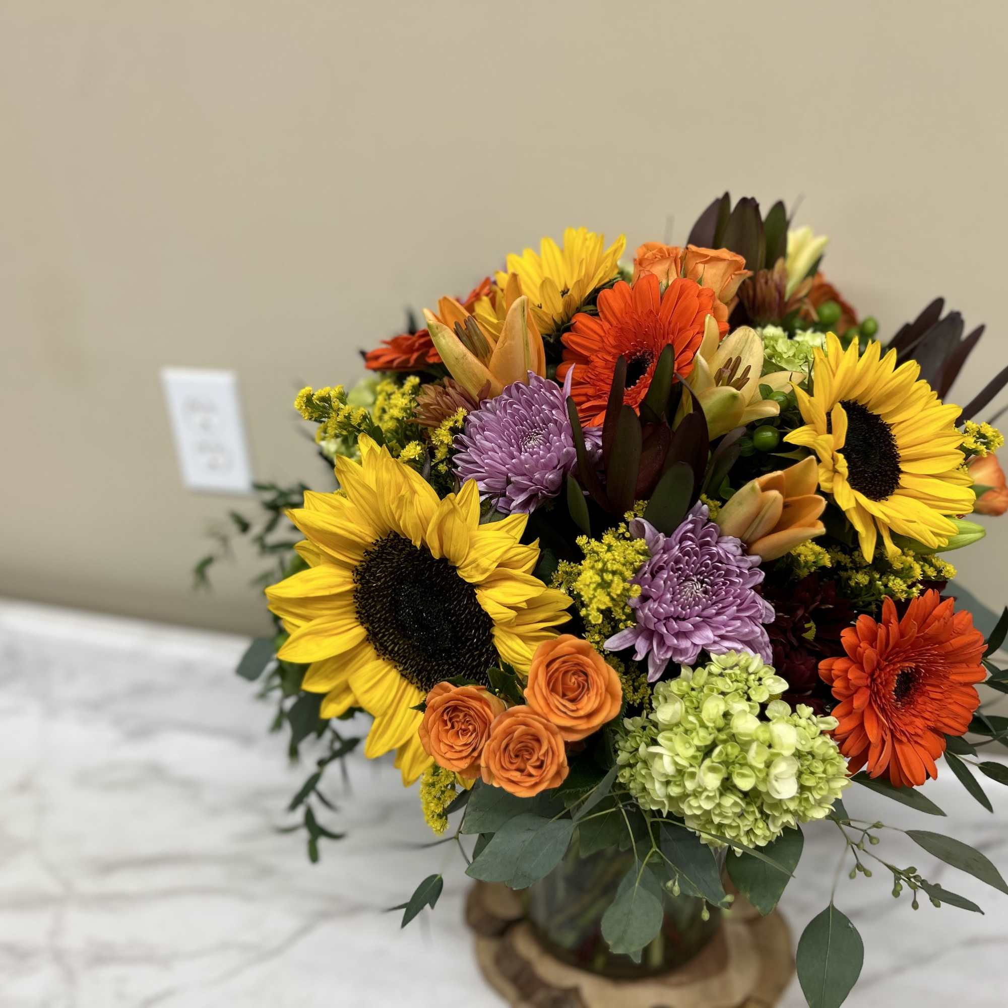 Mixed bouquet with sunflowers, gerbera daisies, and chrysanthemums in a glass vase