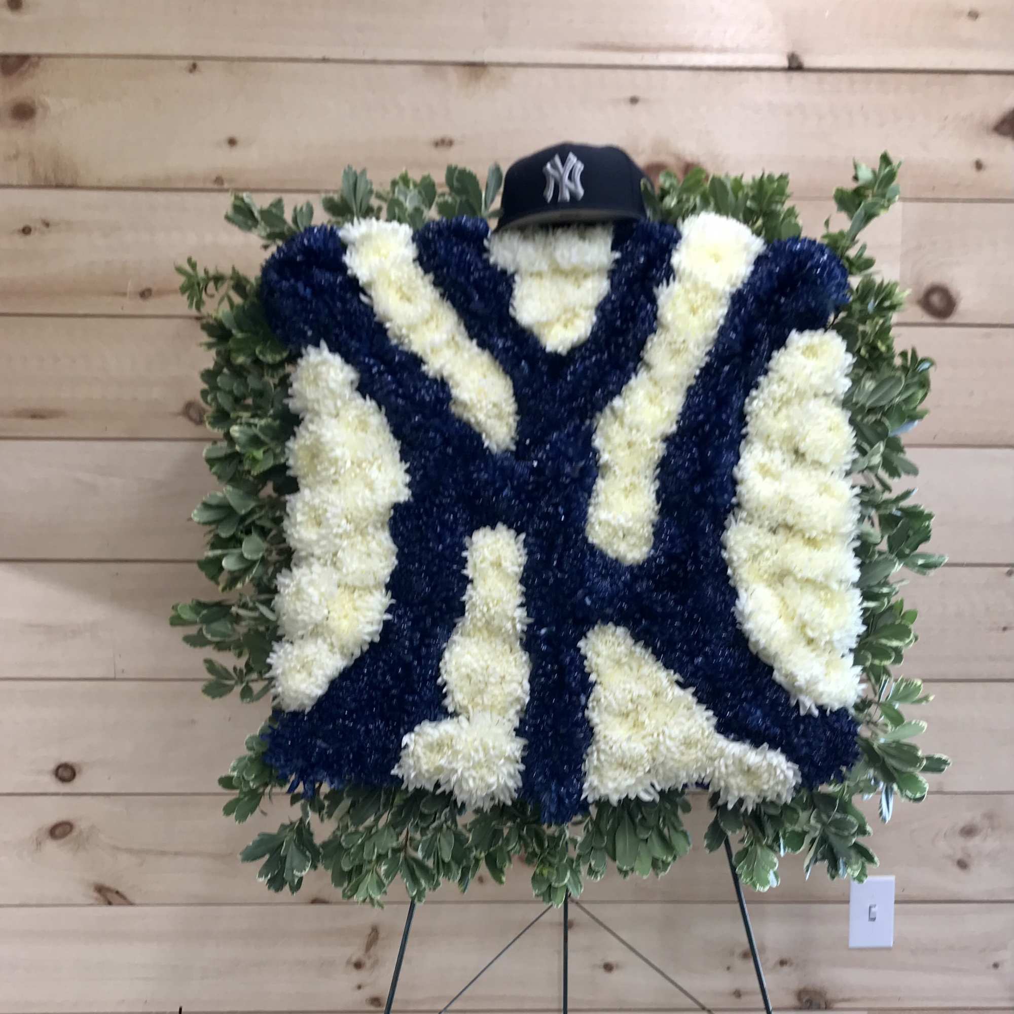 New York Yankees floral tribute with blue and white flowers and a baseball cap