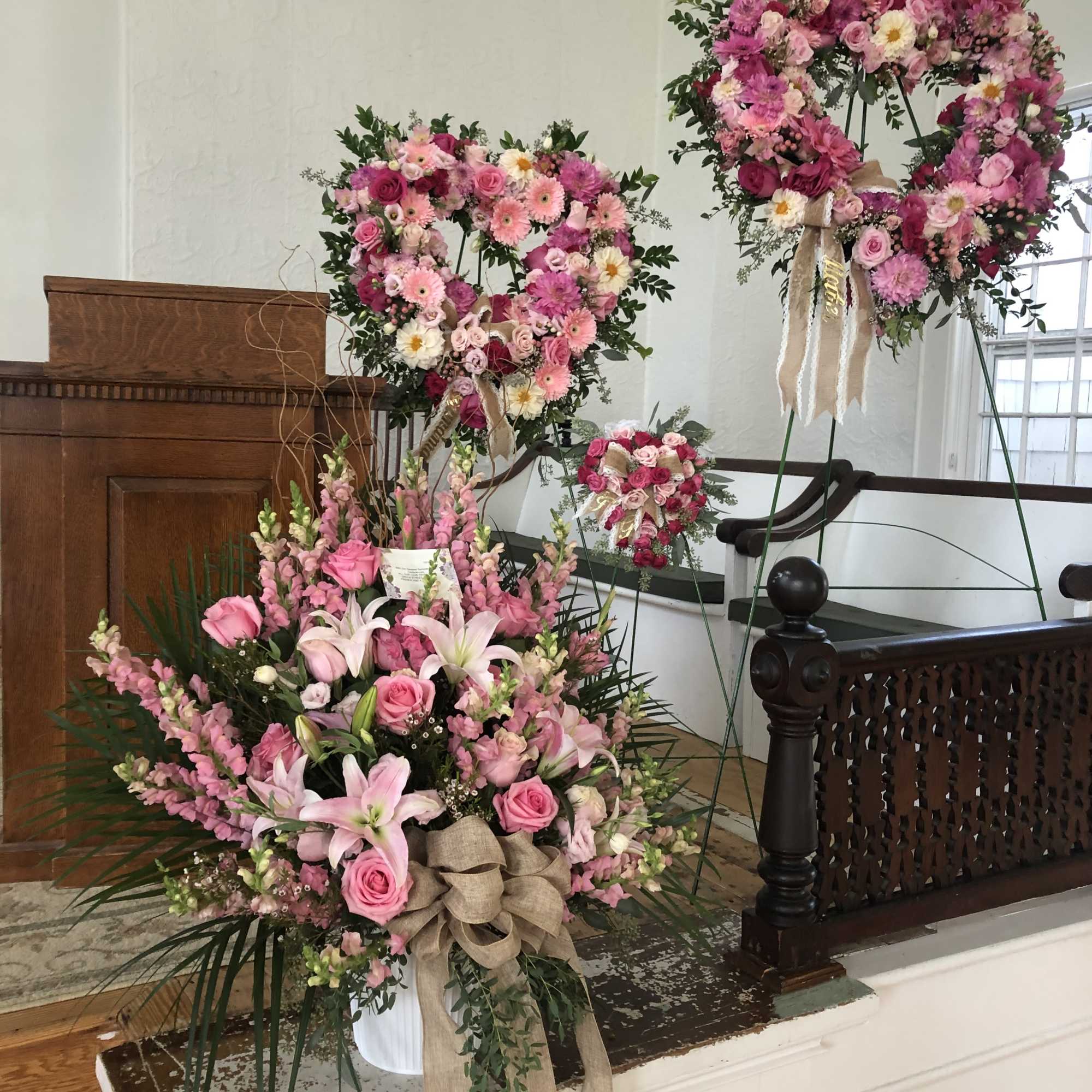 Pink floral funeral wreaths and an arrangement with lilies and roses