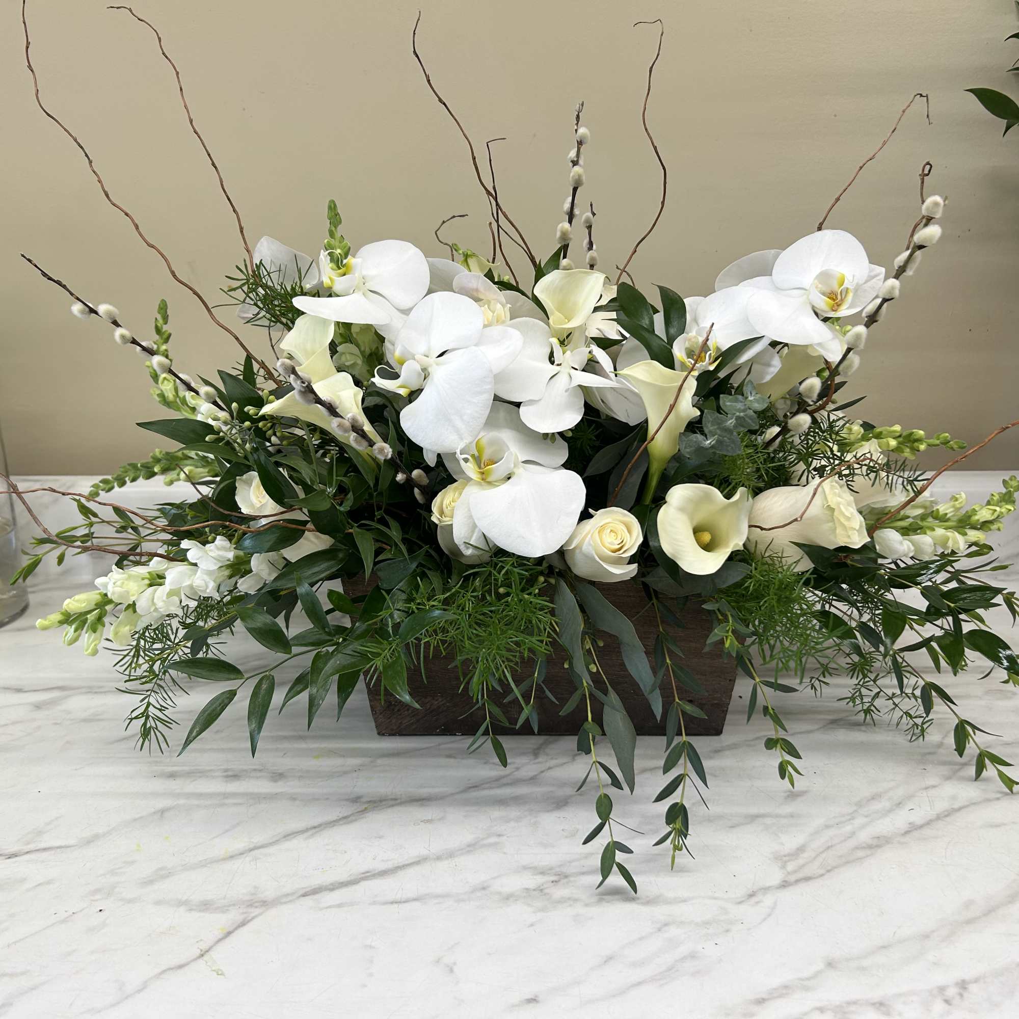 White orchids and calla lilies arranged in a low rectangular container