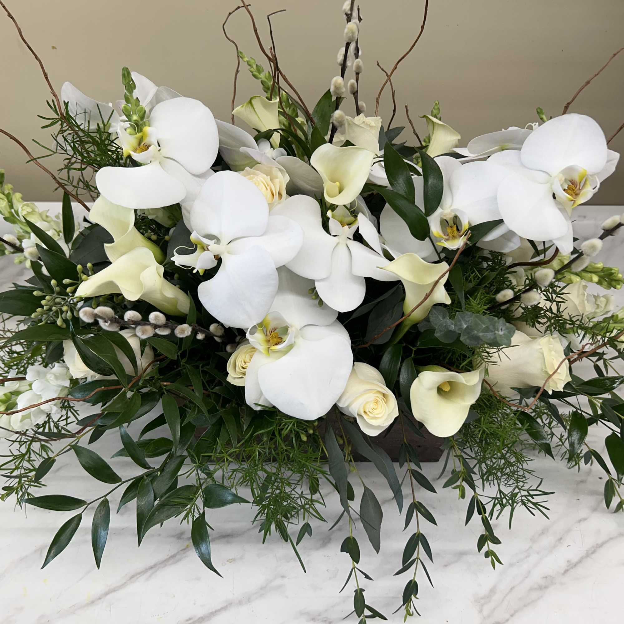 White orchids and cream calla lilies in a low floral arrangement
