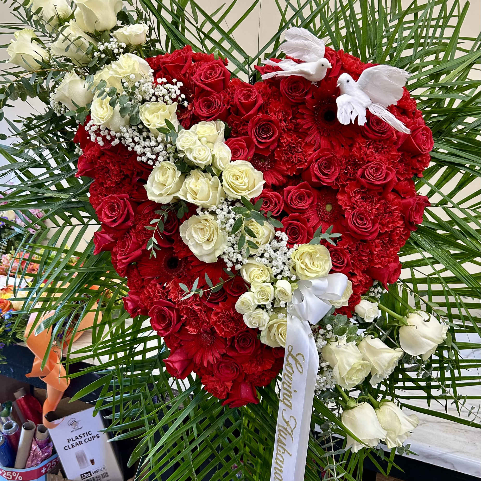 Heart-shaped red and white rose arrangement with white doves
