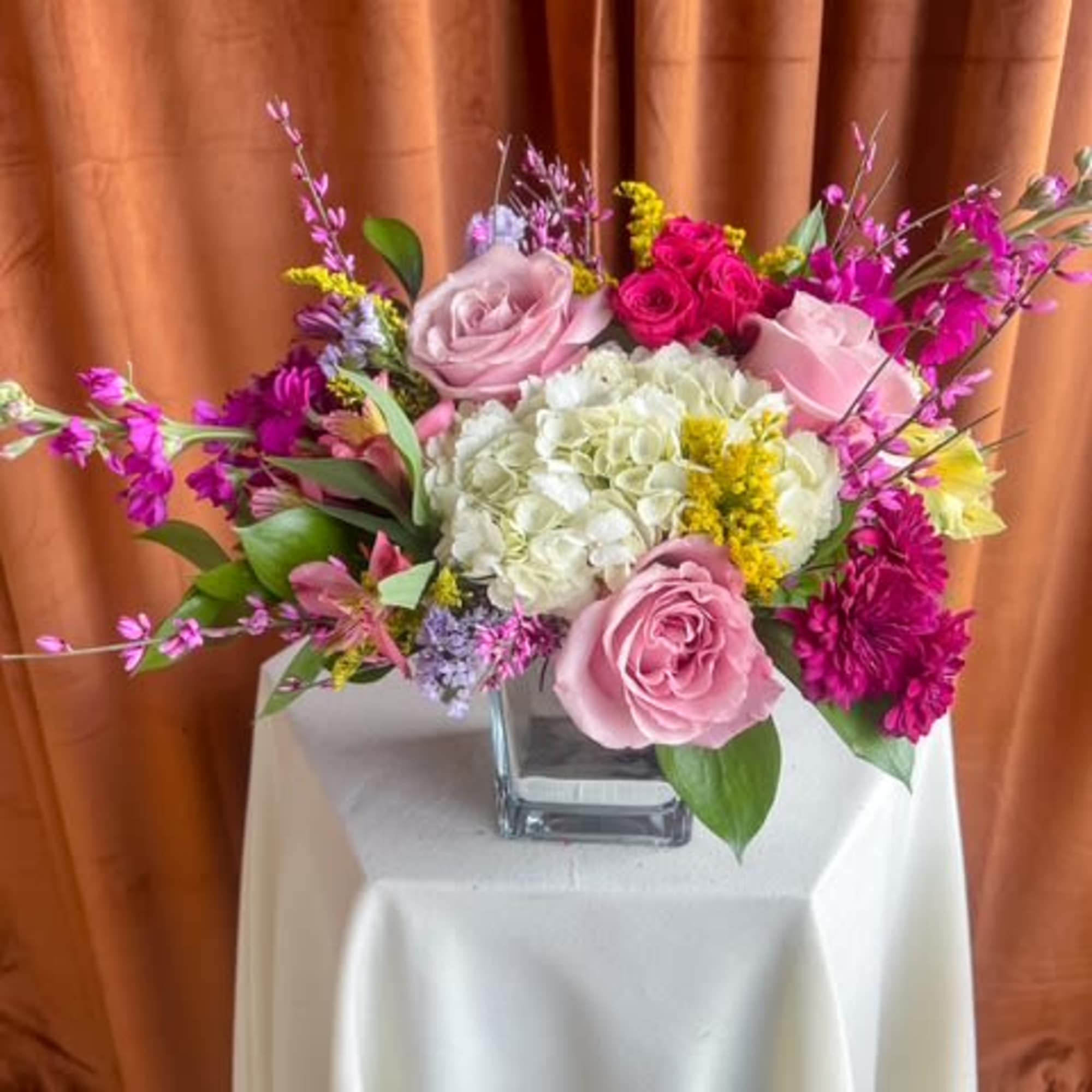 Pink and white rose arrangement in a square glass vase