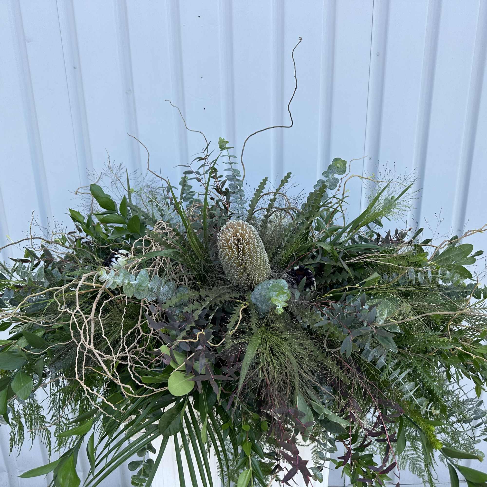 Large greenery arrangement with a central cream protea-like bloom