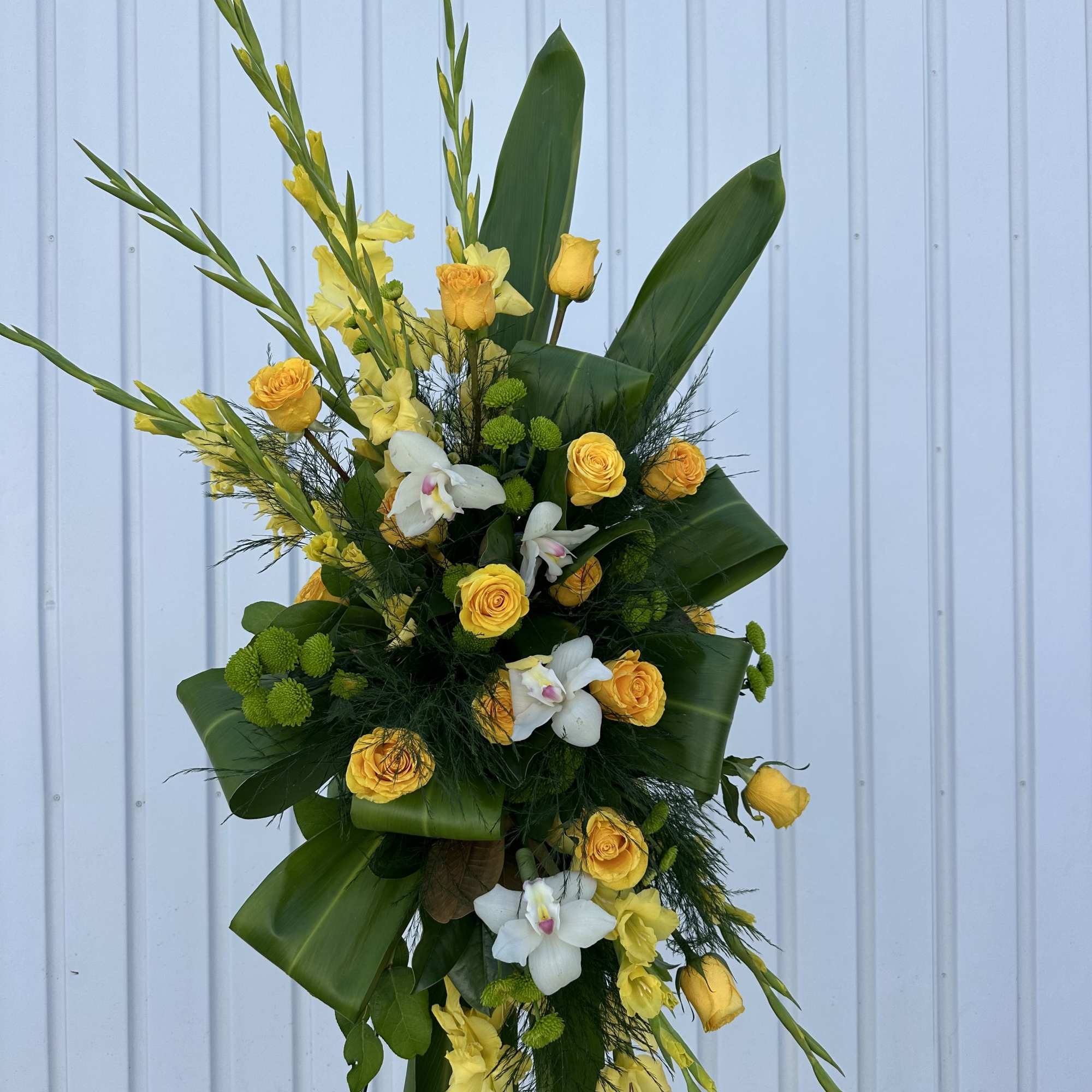A gorgeous standing spray, full of lush greens and golden shades of