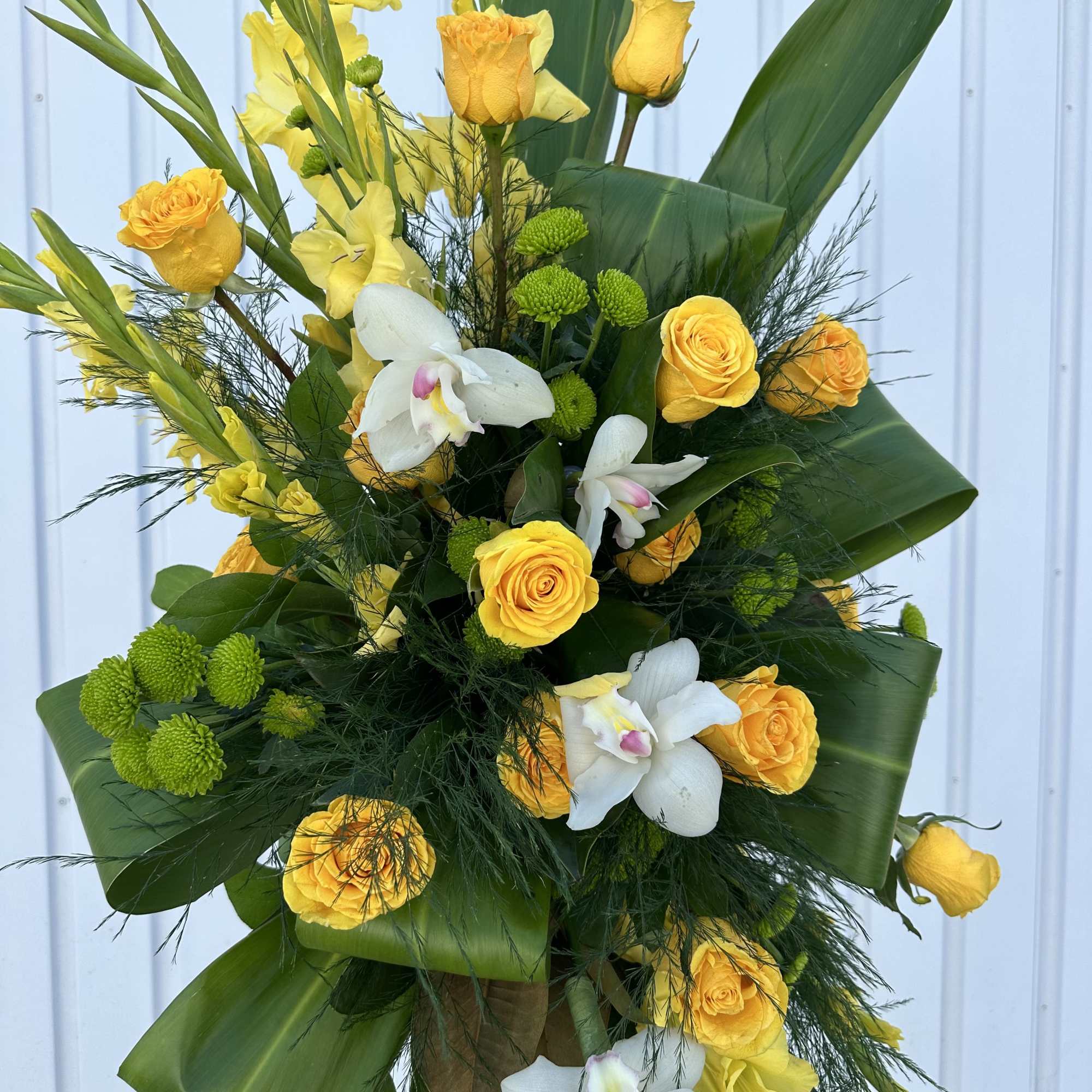 A gorgeous standing spray, full of lush greens and golden shades of