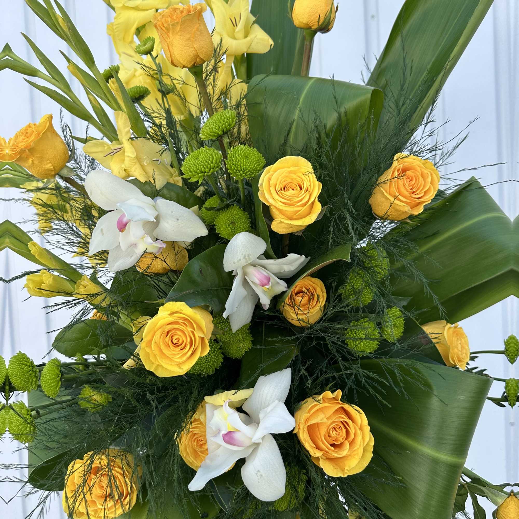 A gorgeous standing spray, full of lush greens and golden shades of