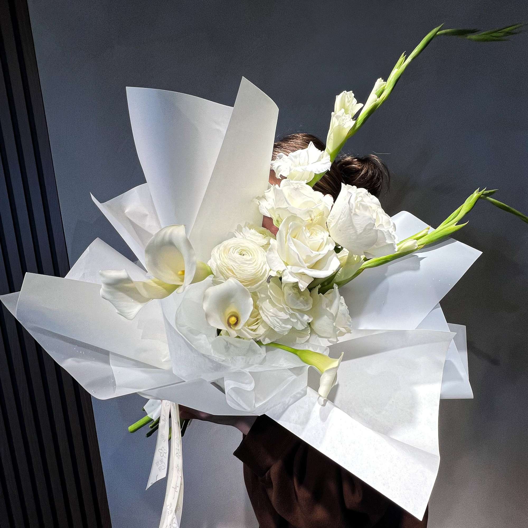 White bouquet with calla lilies and roses wrapped in white paper