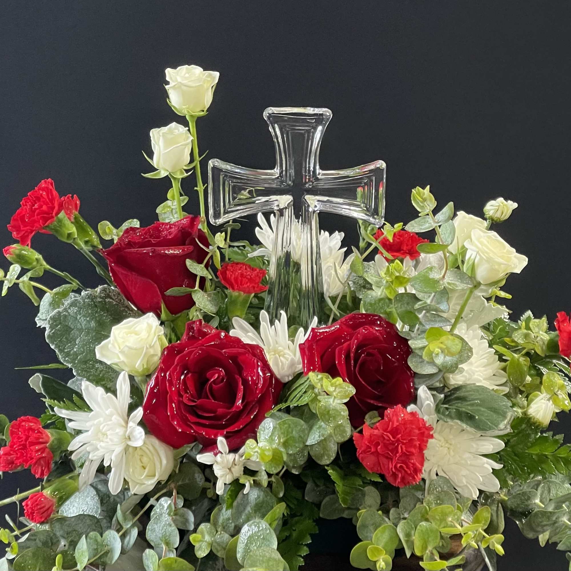 Red and white floral arrangement with a clear glass cross centerpiece