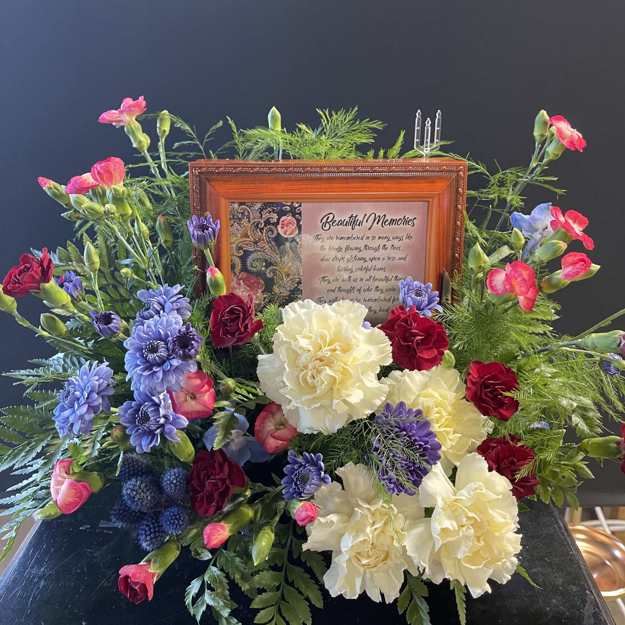 Colorful floral arrangement around a framed memorial plaque